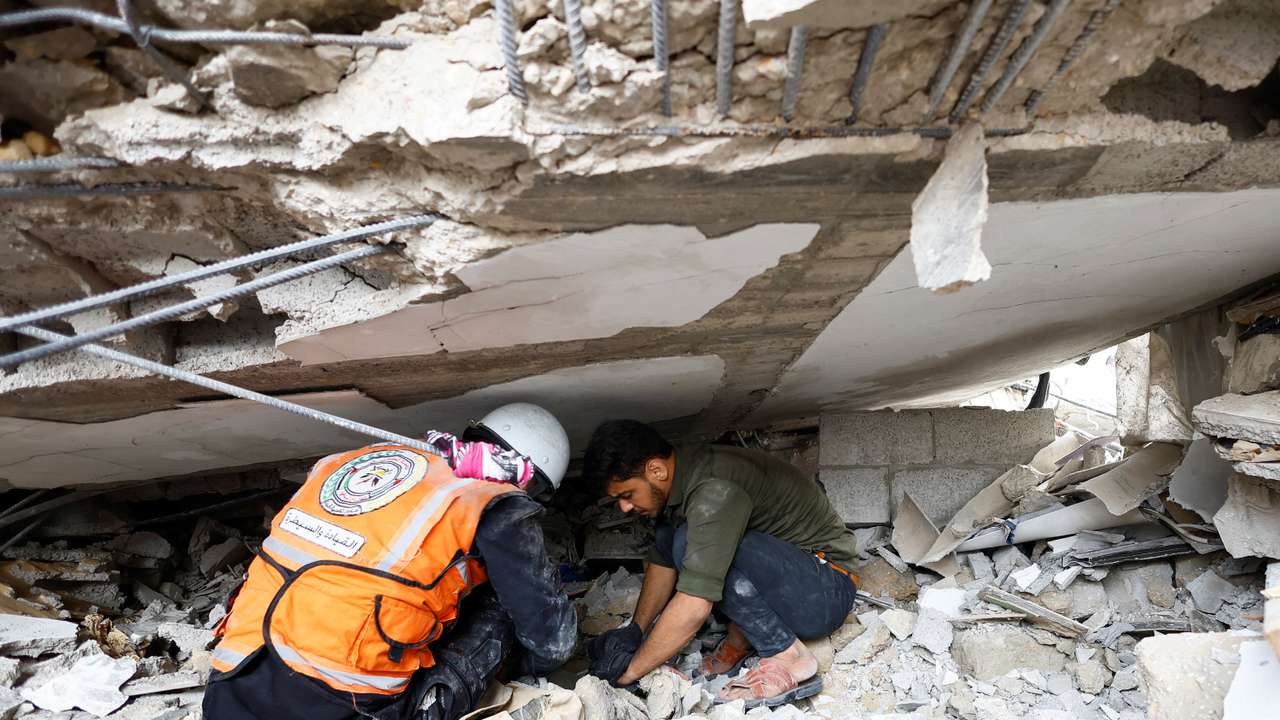 Emergency personnel and people check the damage at the site of Israeli strikes on houses in Khan Younis