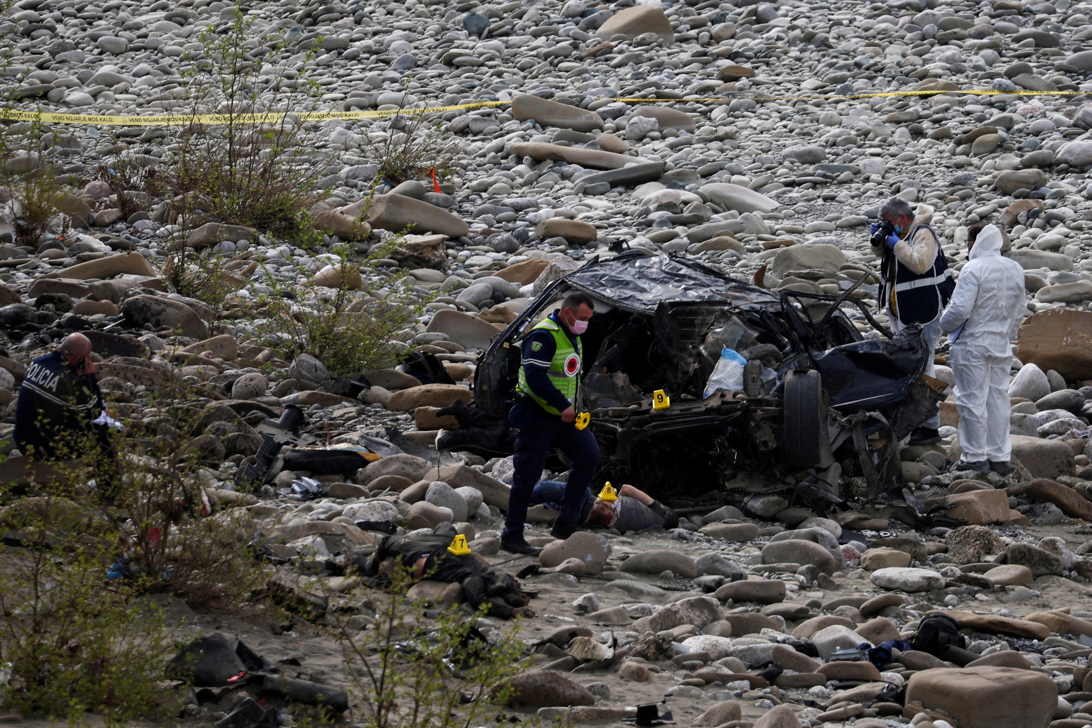 Police officers inspect the scene of a deadly car crash, near Kelcyre