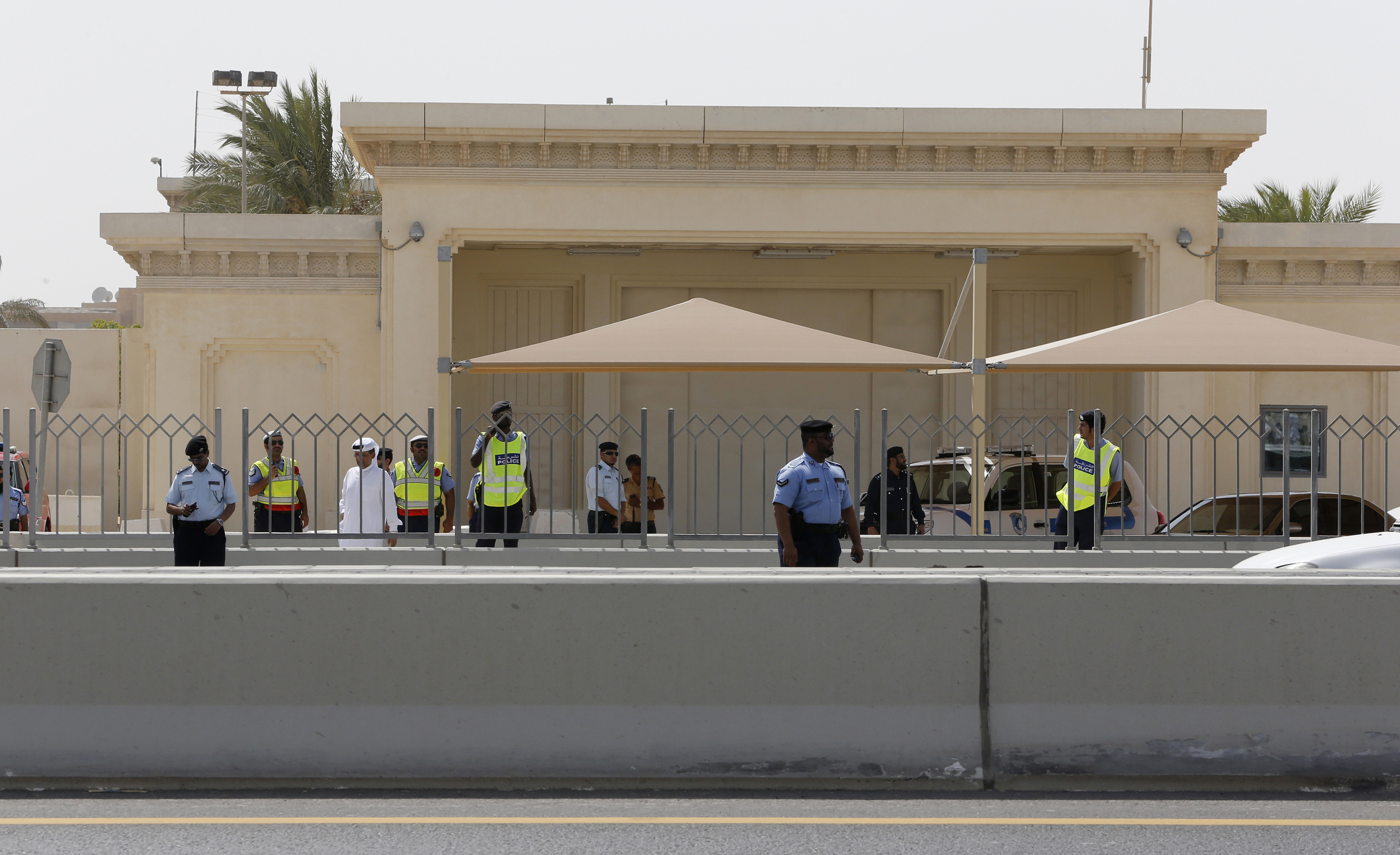 Police officers stand guard as protesters approach the front of the U.S. embassy in Doha