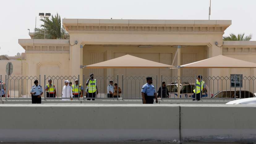 Police officers stand guard as protesters approach the front of the U.S. embassy in Doha