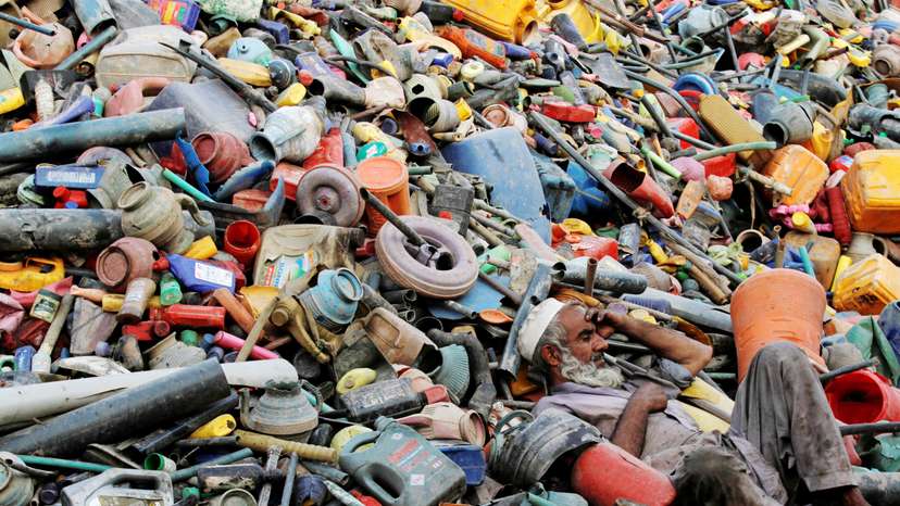 A labourer rests over a pile of recyclables at a yard in Peshawar