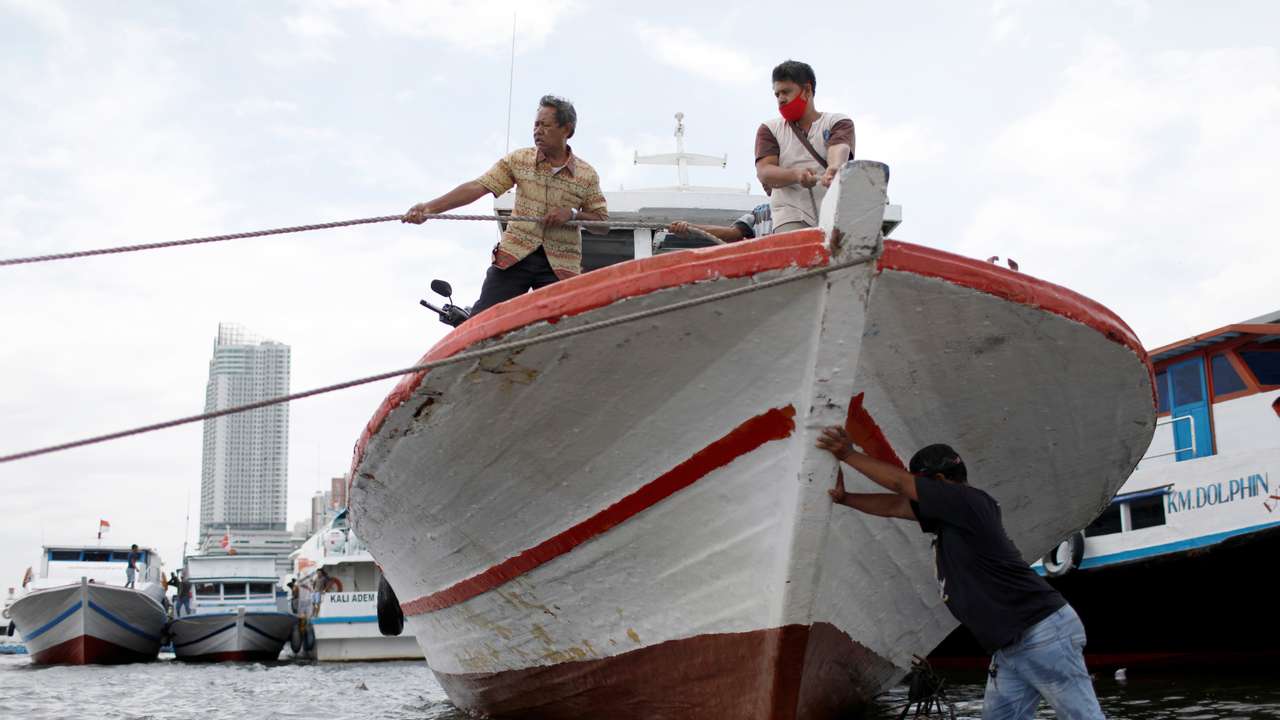 A man pushes a boat at Kali Adem port, north of Jakarta