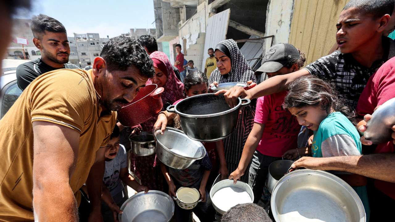 FILE PHOTO: Palestinians eat food cooked by a charity kitchen near houses destroyed in the Israeli military offensive, in Khan Younis in the southern Gaza Strip