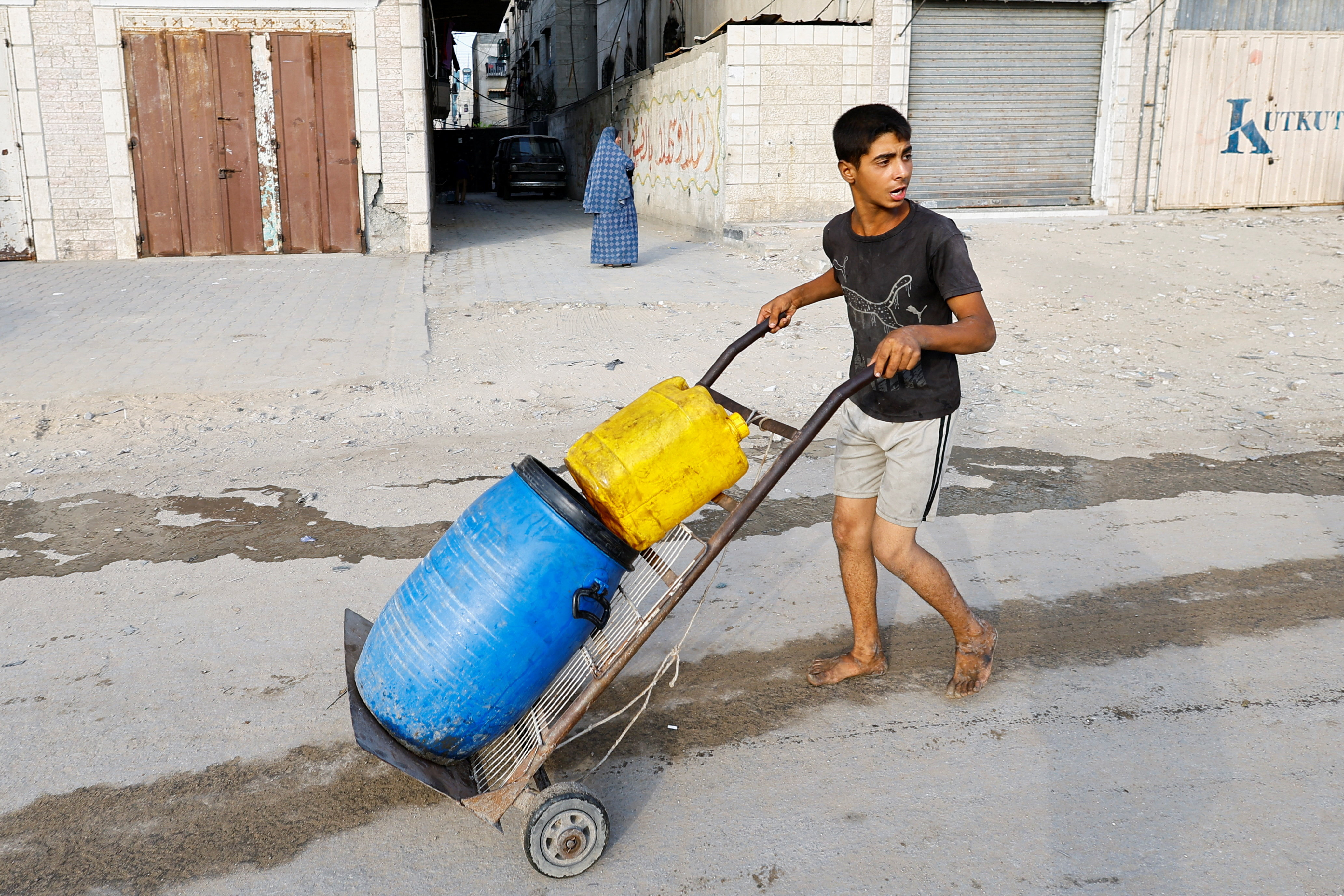 Palestinians wait to collect water amid shortages, in Gaza City