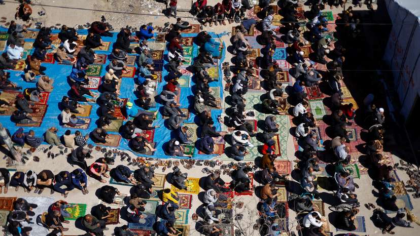 Palestinians perform first Friday prayers during Ramadan near the ruins of a destroyed mosquein, in Rafah
