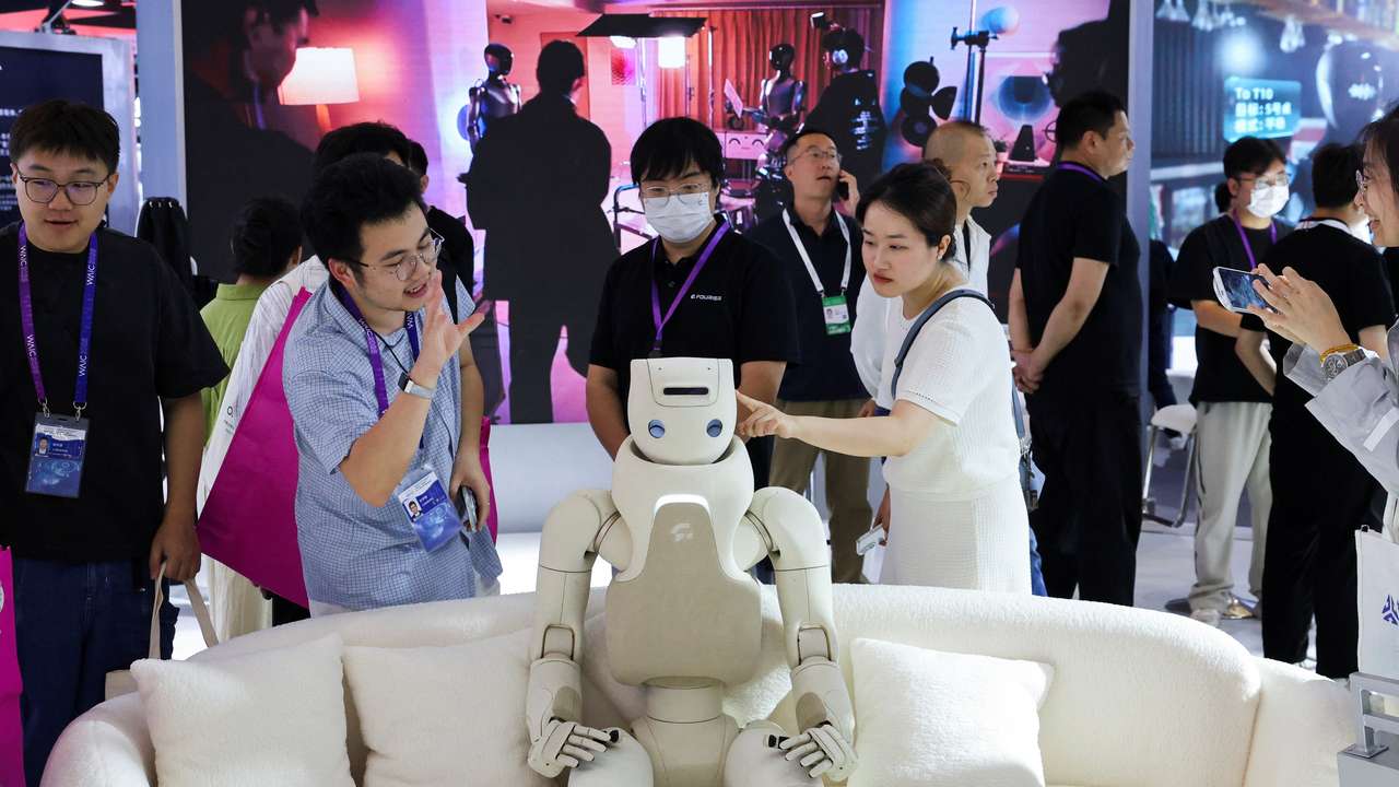 People interact with a humanoid robot at Fourier booth during WAIC in Shanghai