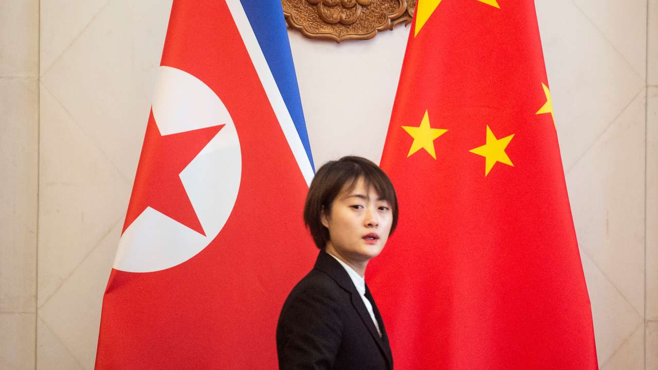 A Chinese hostess walks past North Korean and Chinese flags before the meeting between North Korean Foreign Minister Ri Yong Ho and China's Foreign Minister Wang Yi at the Diaoyutai State Guesthouse in Beijing