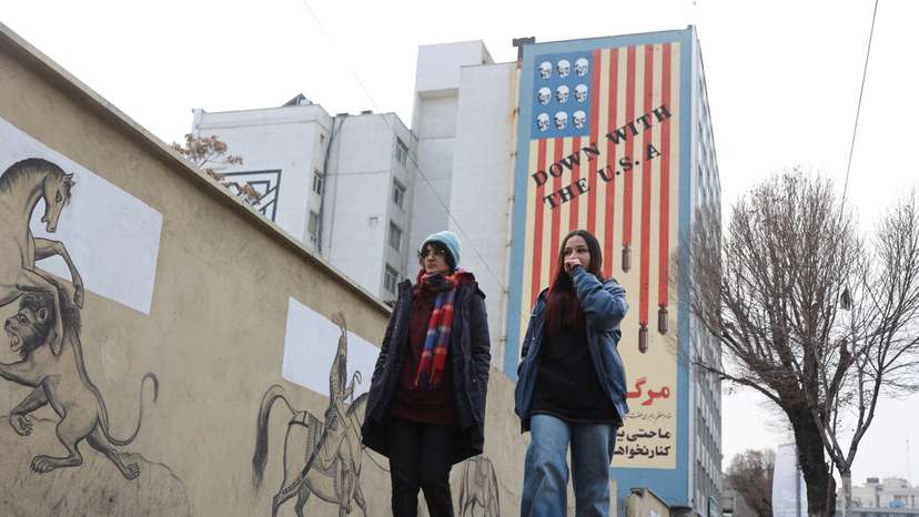 FILE PHOTO: People walk next to an anti-US mural on a street as protests erupt over the collapse of the currency's value in Tehran