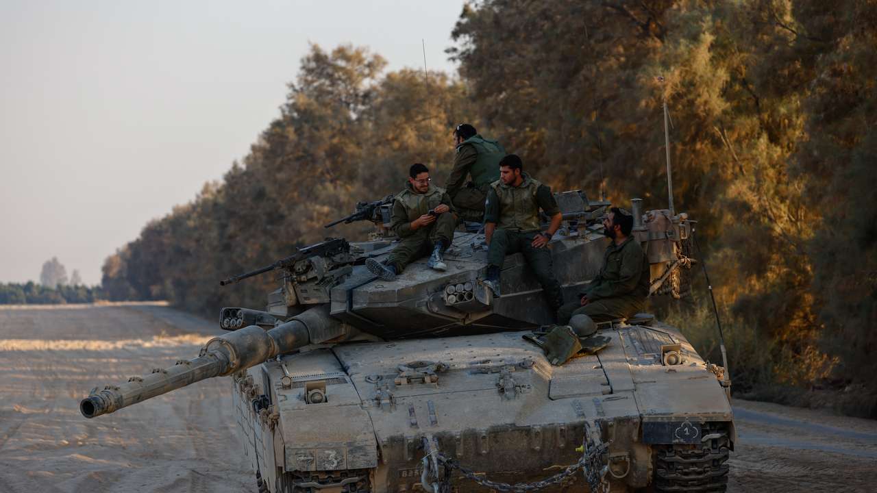 Israeli soldiers rest on top of their tank near the Israel-Gaza border