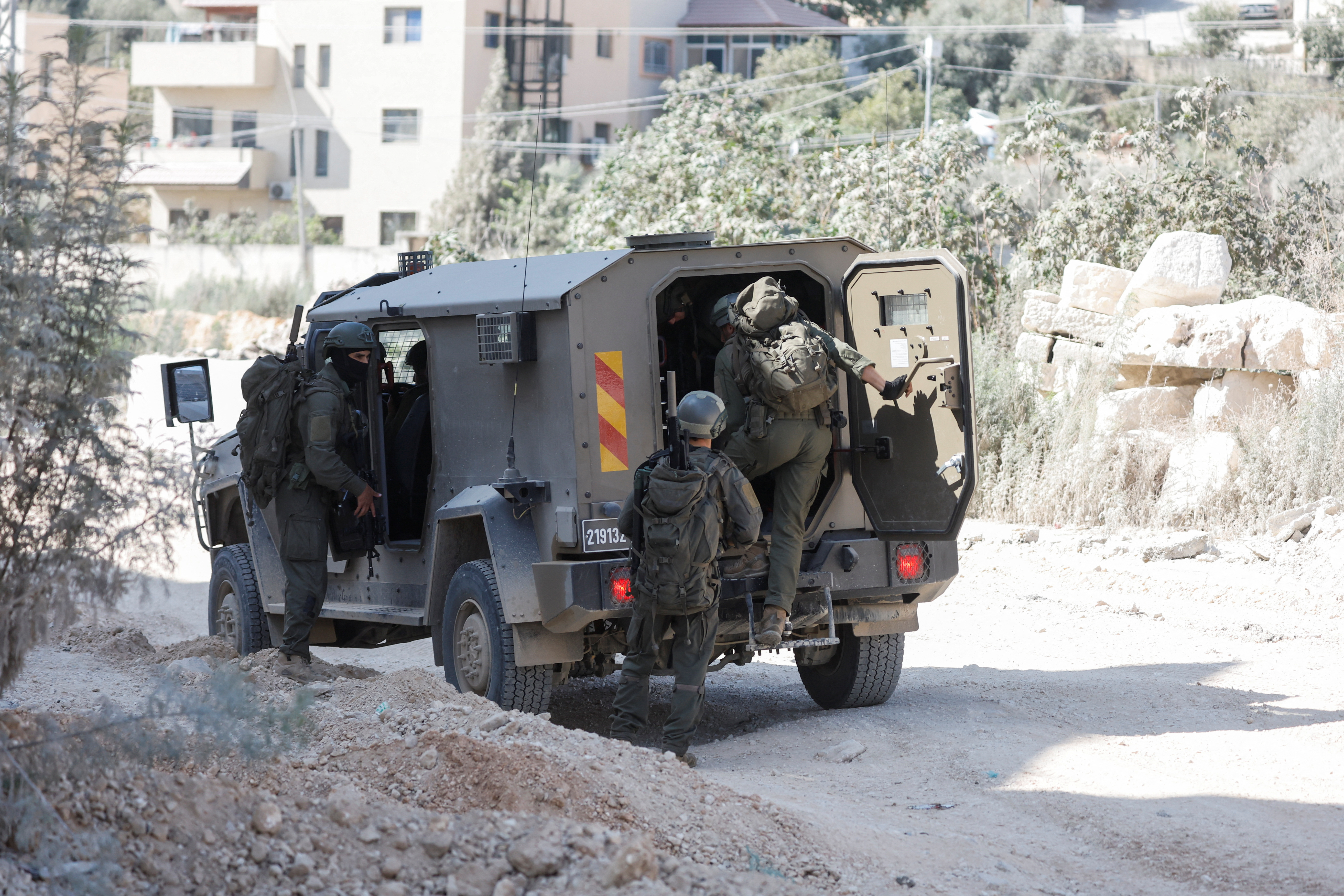 Israeli soldiers stand near a military vehicle during an Israeli raid in Nour Shams camp in Tulkarm