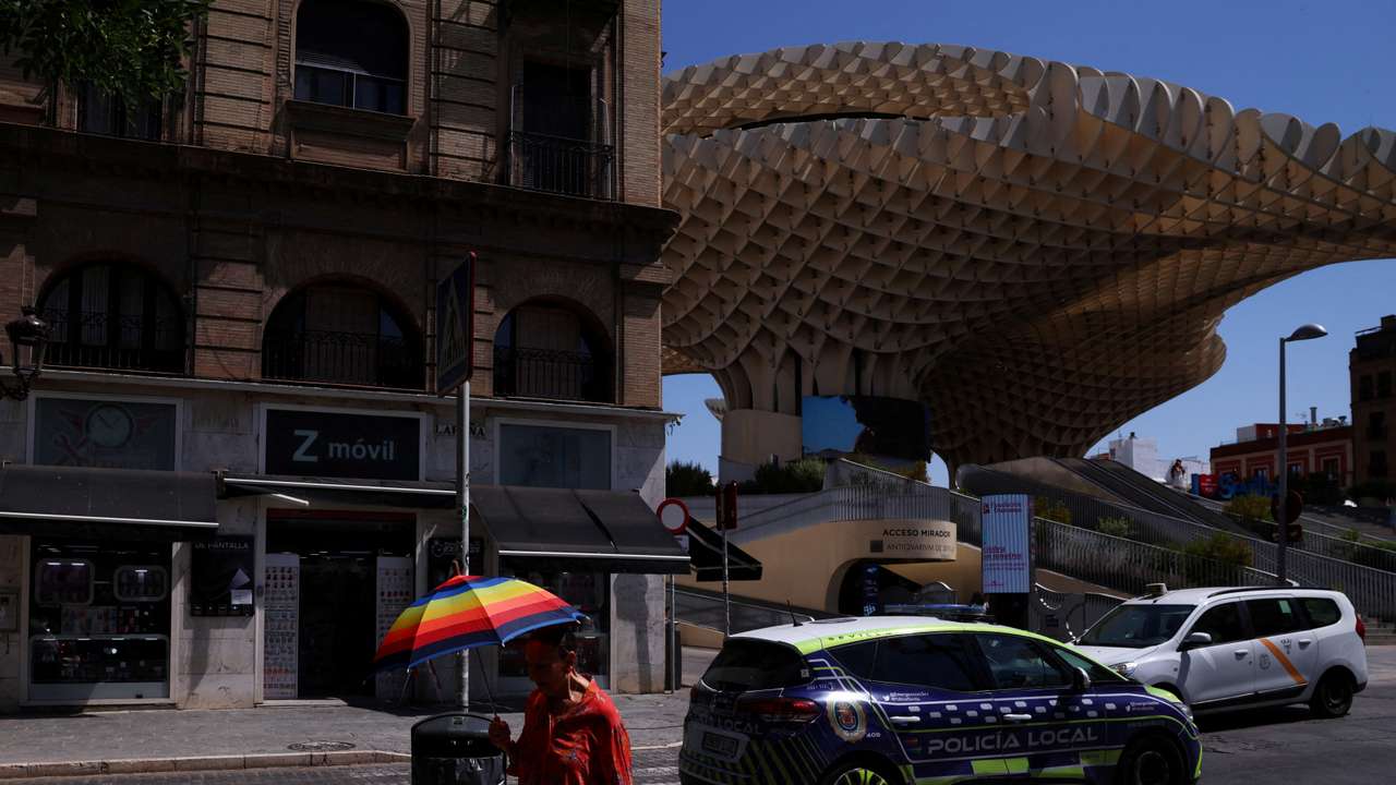 A woman carries an umbrella nearby Las Setas during a heatwave in Seville