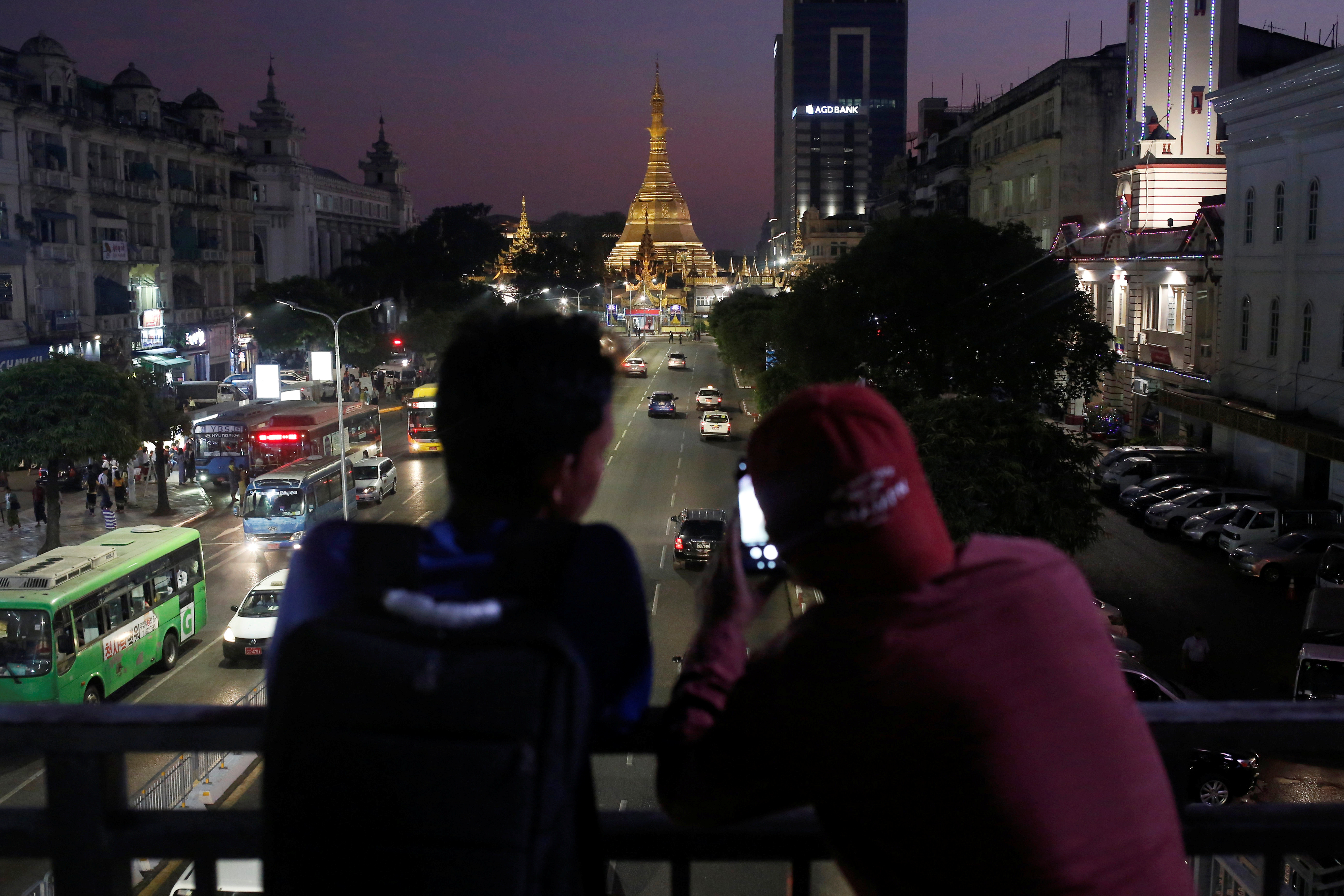 Two boys take photos of the Sule Pagoda during sunset hours in Yangon