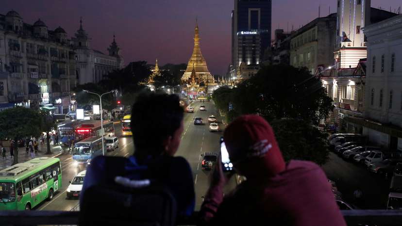Two boys take photos of the Sule Pagoda during sunset hours in Yangon