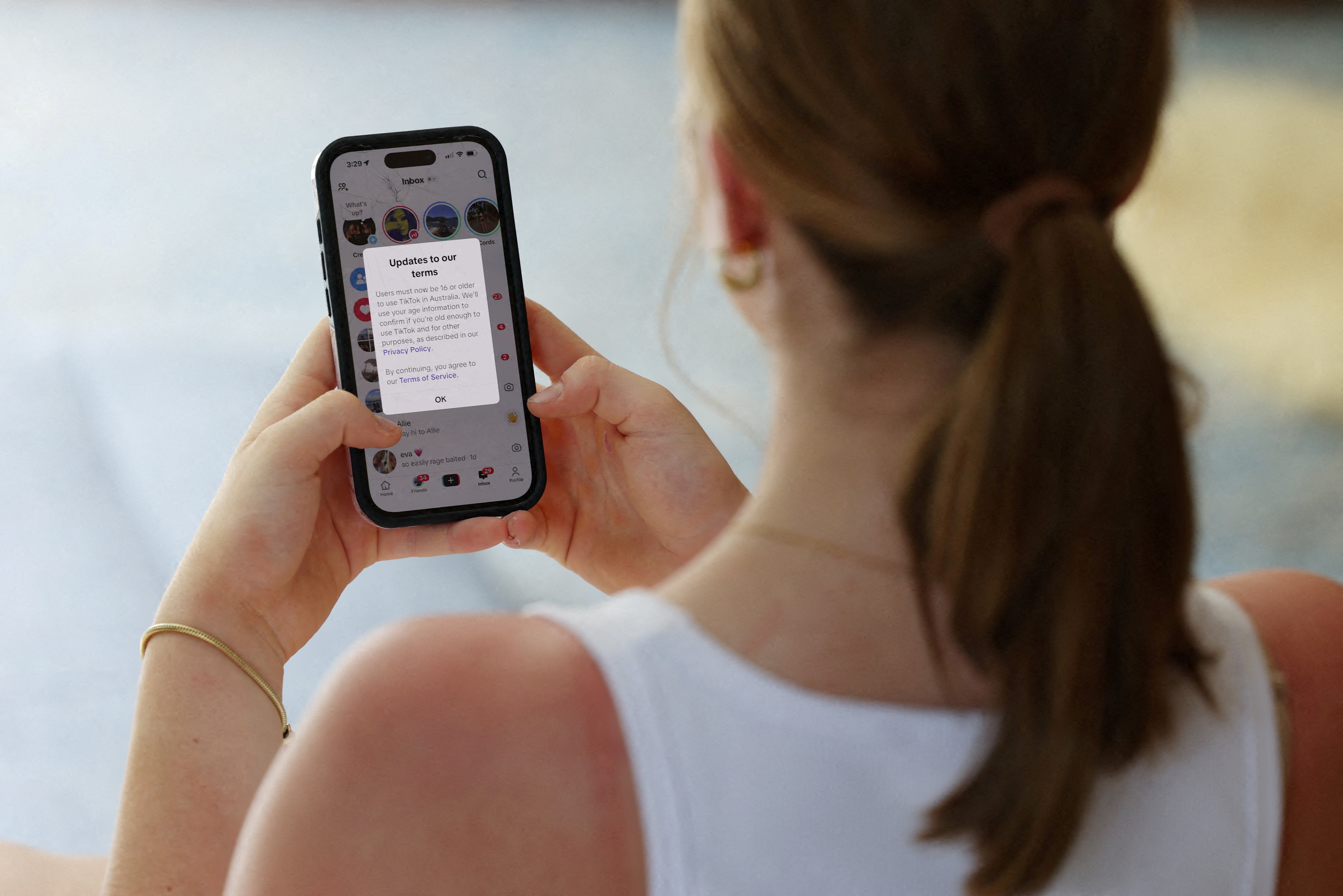 A teenager poses holding a mobile phone displaying a message from TikTok in Sydney