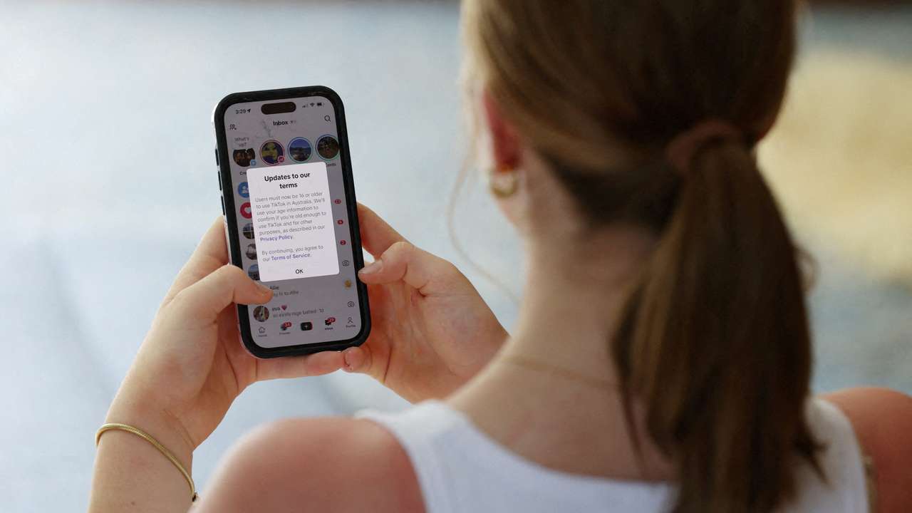 A teenager poses holding a mobile phone displaying a message from TikTok in Sydney