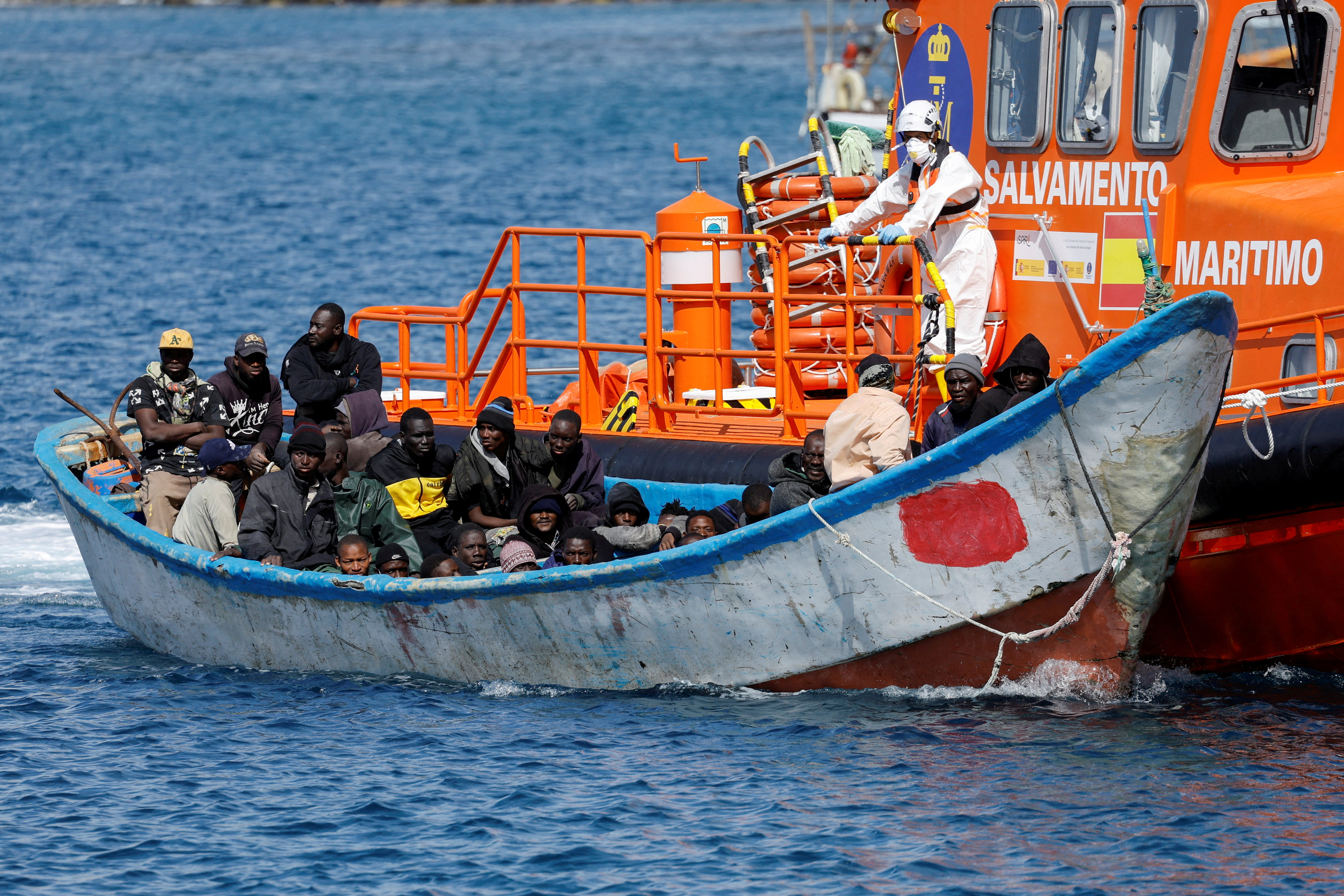 FILE PHOTO: Migrants wait to disembark from a fiber boat after being rescued by a Spanish coast guard vessel in the port of Arguineguin