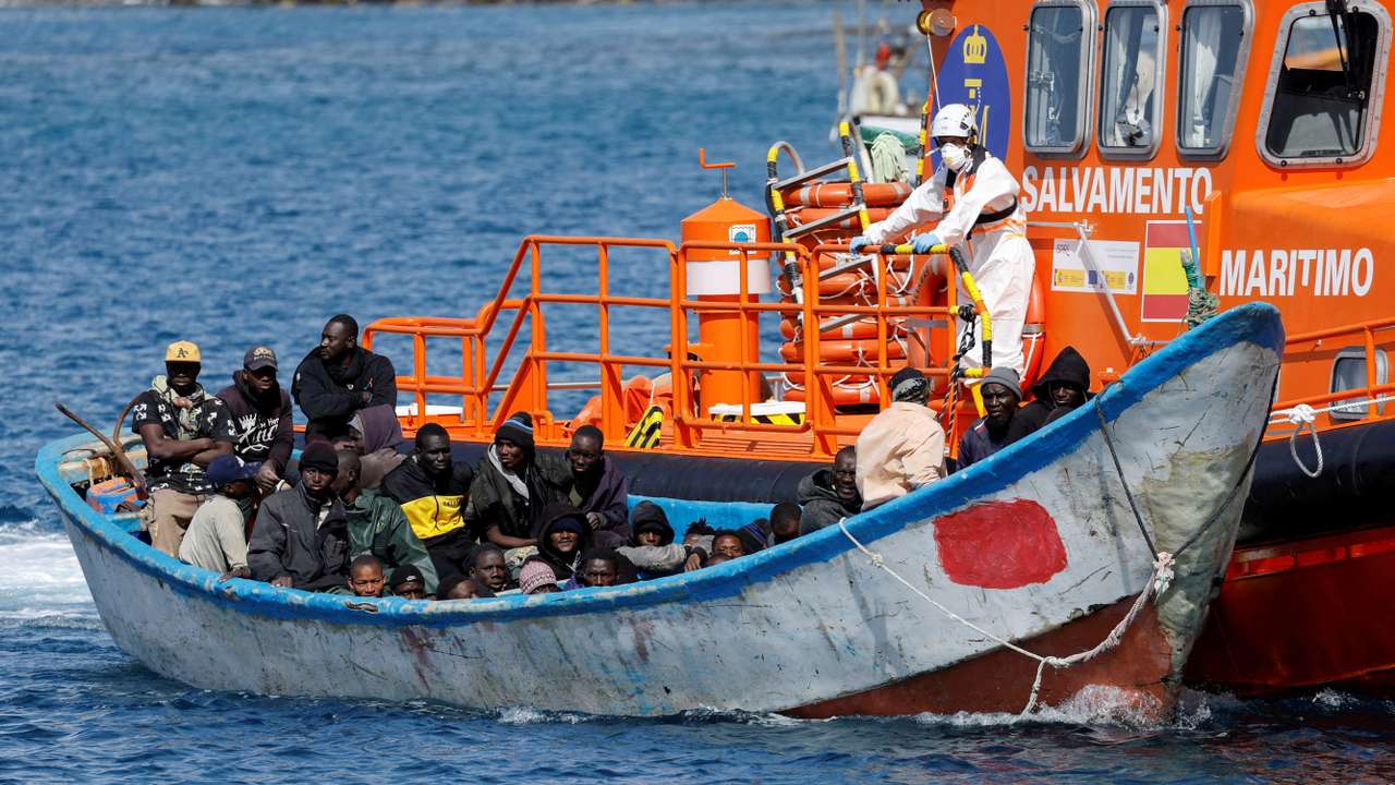 FILE PHOTO: Migrants wait to disembark from a fiber boat after being rescued by a Spanish coast guard vessel in the port of Arguineguin