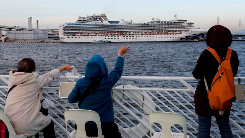 Tourists on a sightseeing cruise ship wave to passengers of the cruise ship Diamond Princess, which is anchored at Daikoku Pier Cruise Terminal in Yokohama