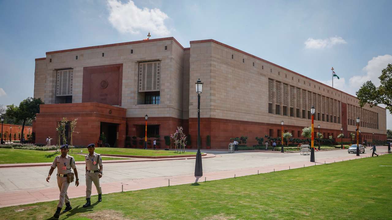Police officers walk in front of India's new parliament building a day before its inauguration in New Delhi