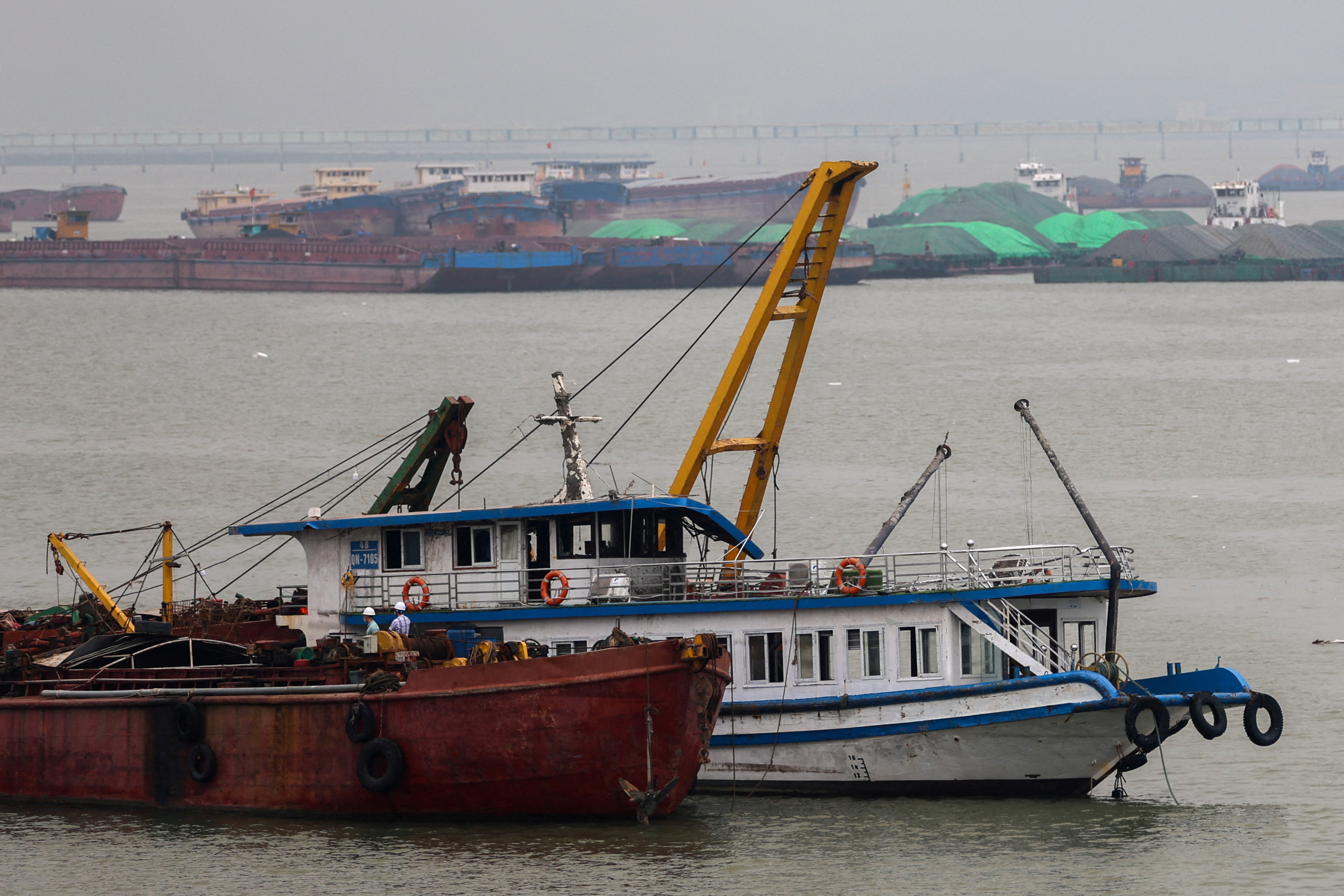 A tourist boat (in white) that capsized in an accident, is towed back to the port, in Halong Bay