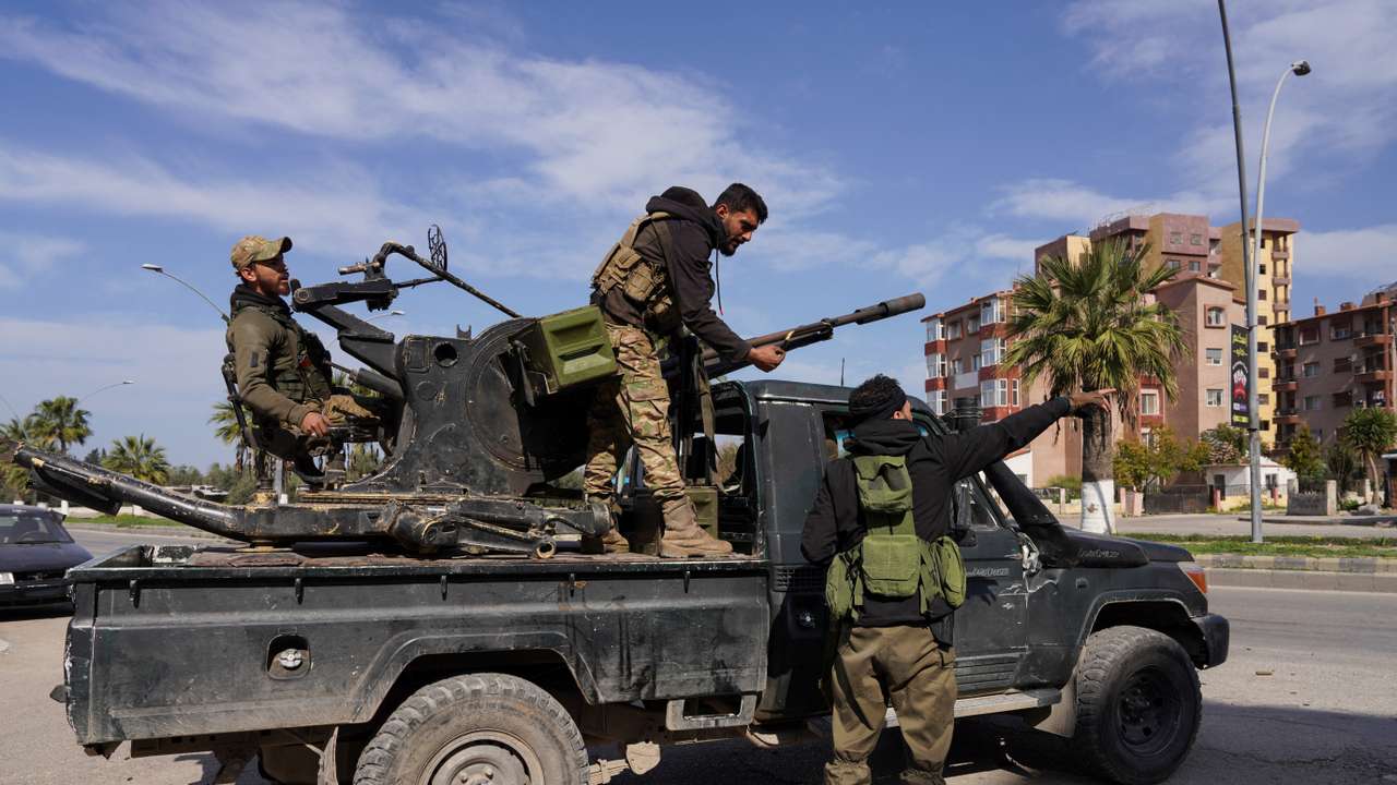 A member of Syrian forces stands on a military truck in Latakia