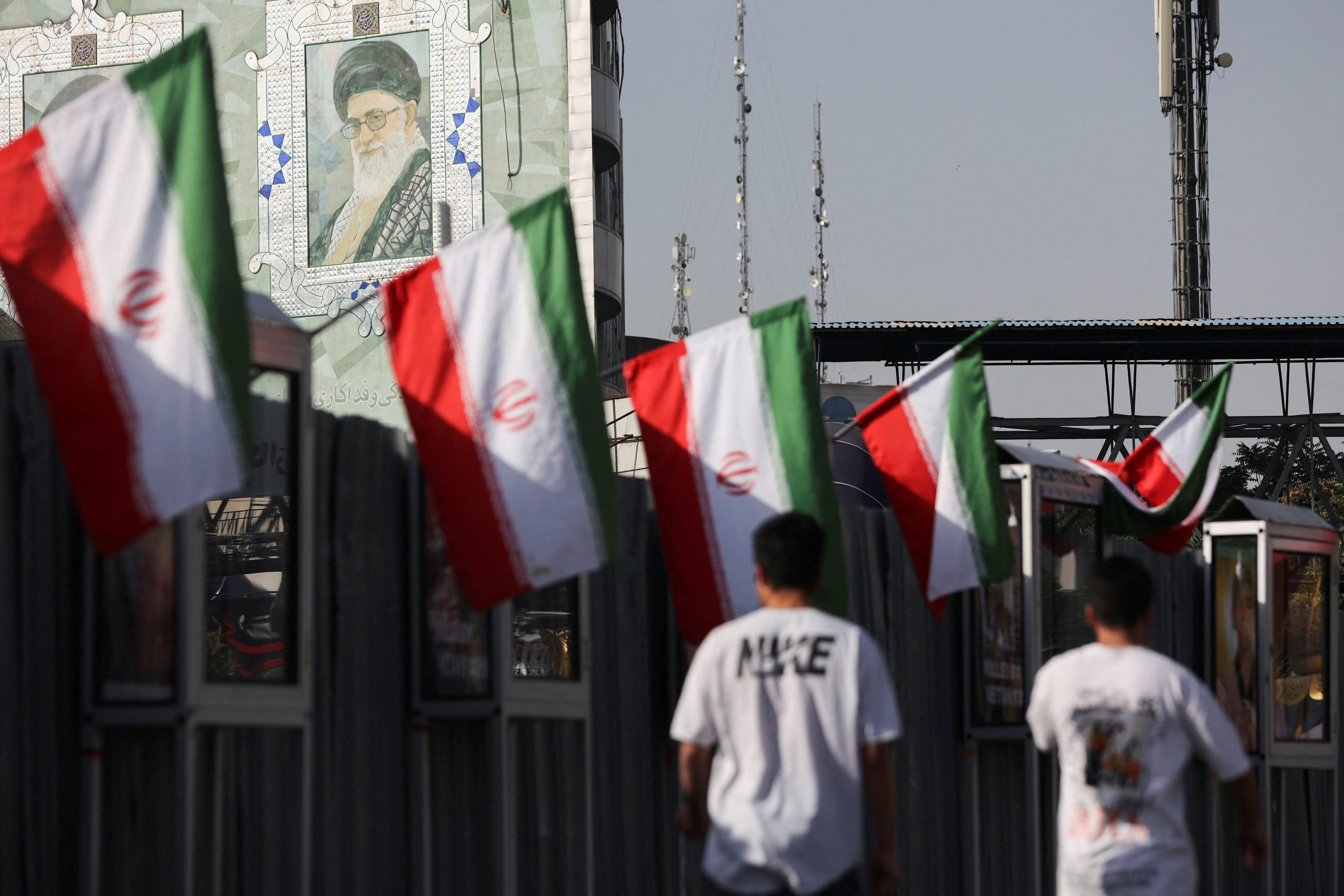 People walk near a mural of Iran's Supreme Leader, Ayatollah Ali Khamenei, in Tehran