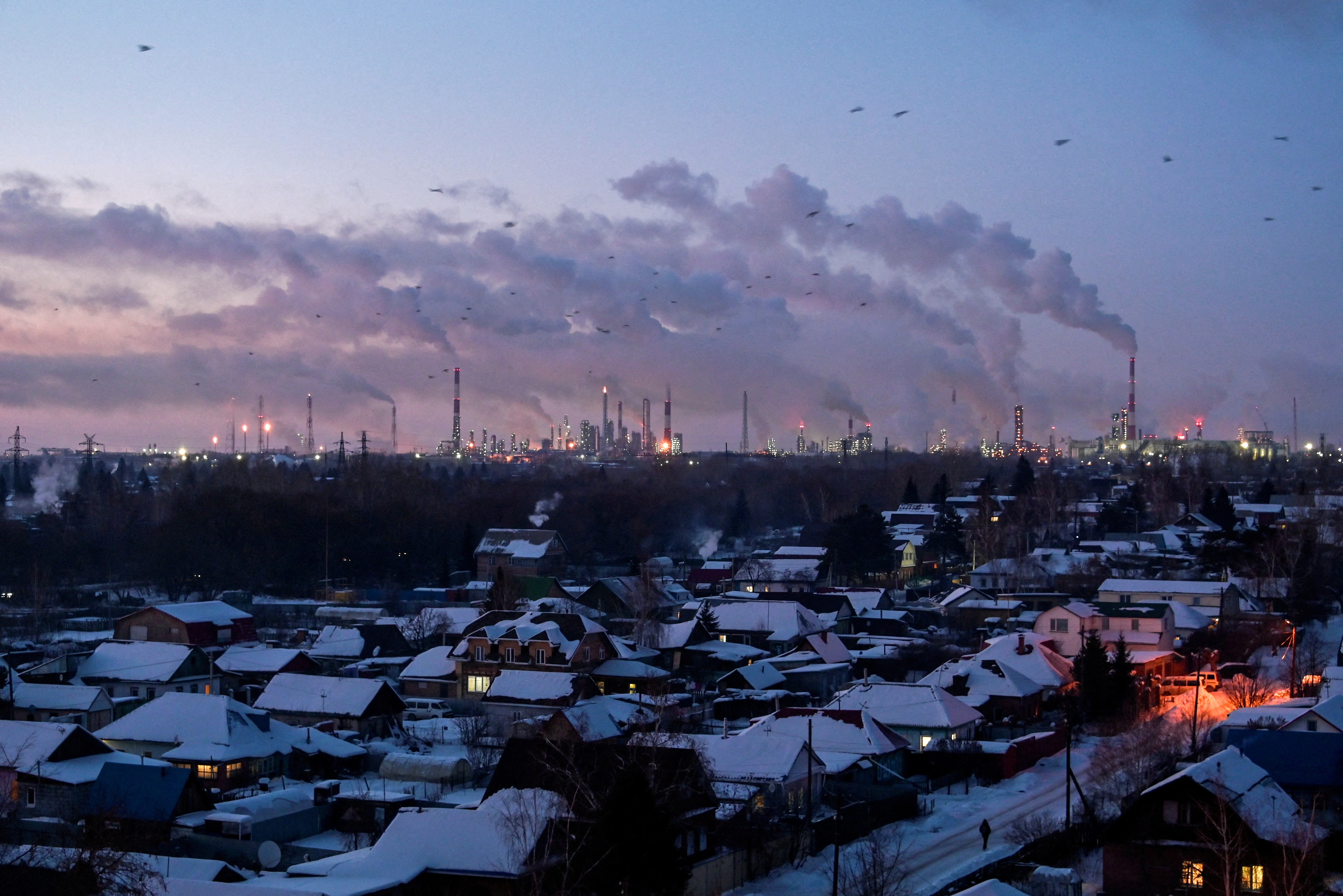 FILE PHOTO: Flue gas and steam rise out of chimneys in Omsk