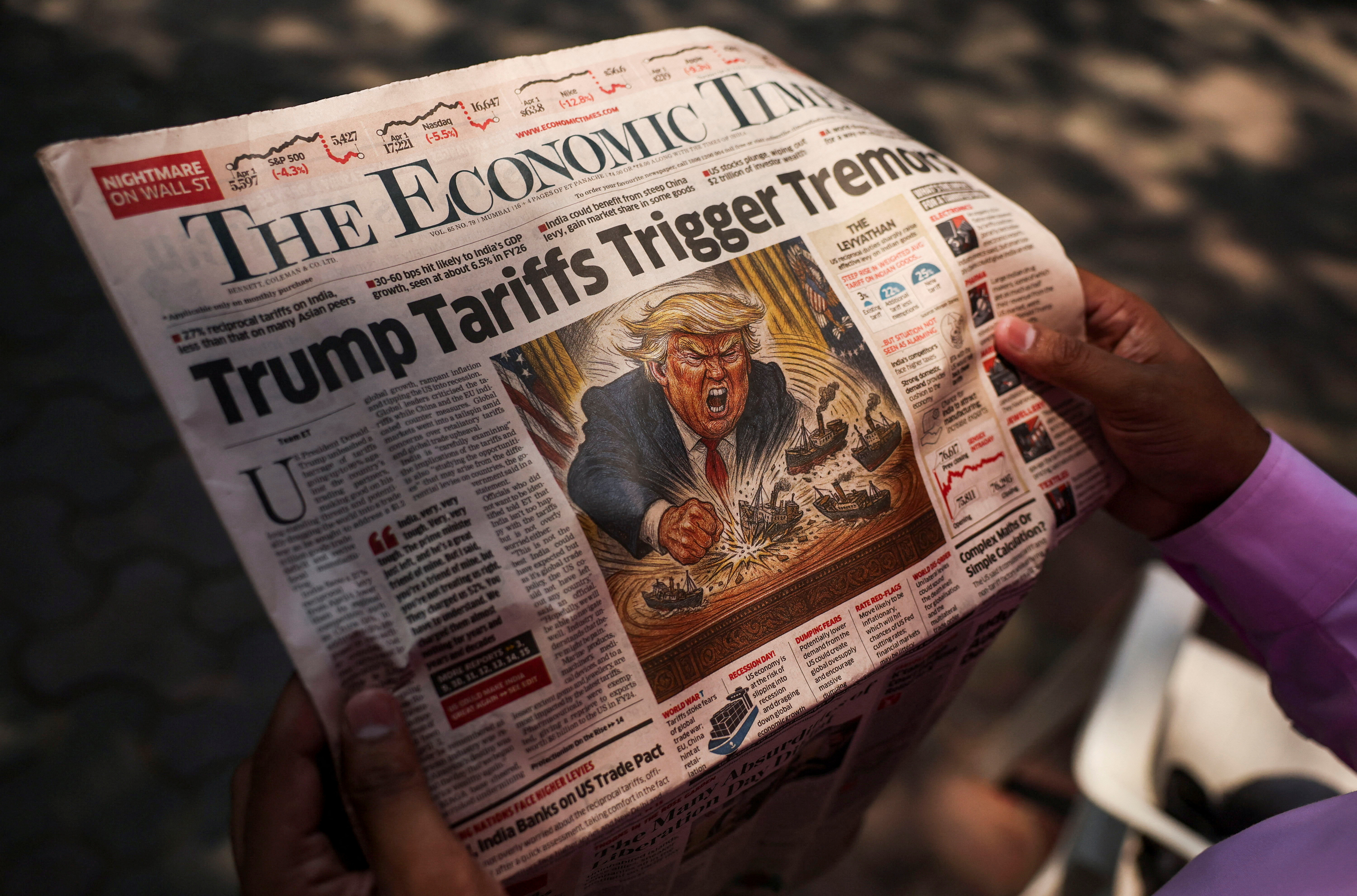 Man reads a newspaper outside the Bombay Stock Exchange (BSE) after Trump's tariff plan announcement, in Mumbai