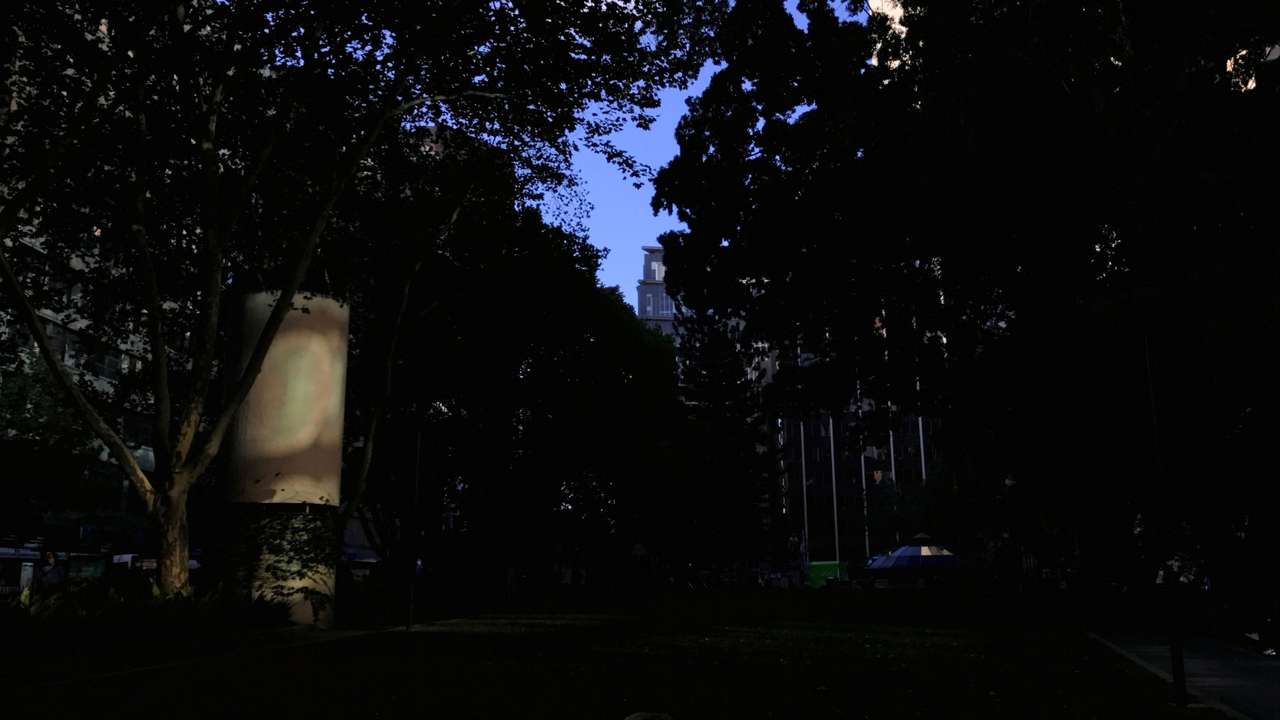A homeless man sleeps under a blanket in a patch of sunlight at a park in central Sydney