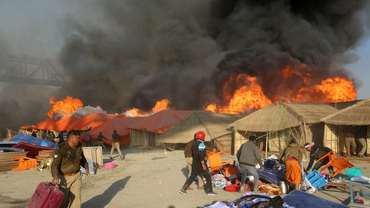 Police officers and volunteers salvage belongings of the devotees after a fire erupts in makeshift tents during the ongoing "Maha Kumbh Mela" in Prayagraj
