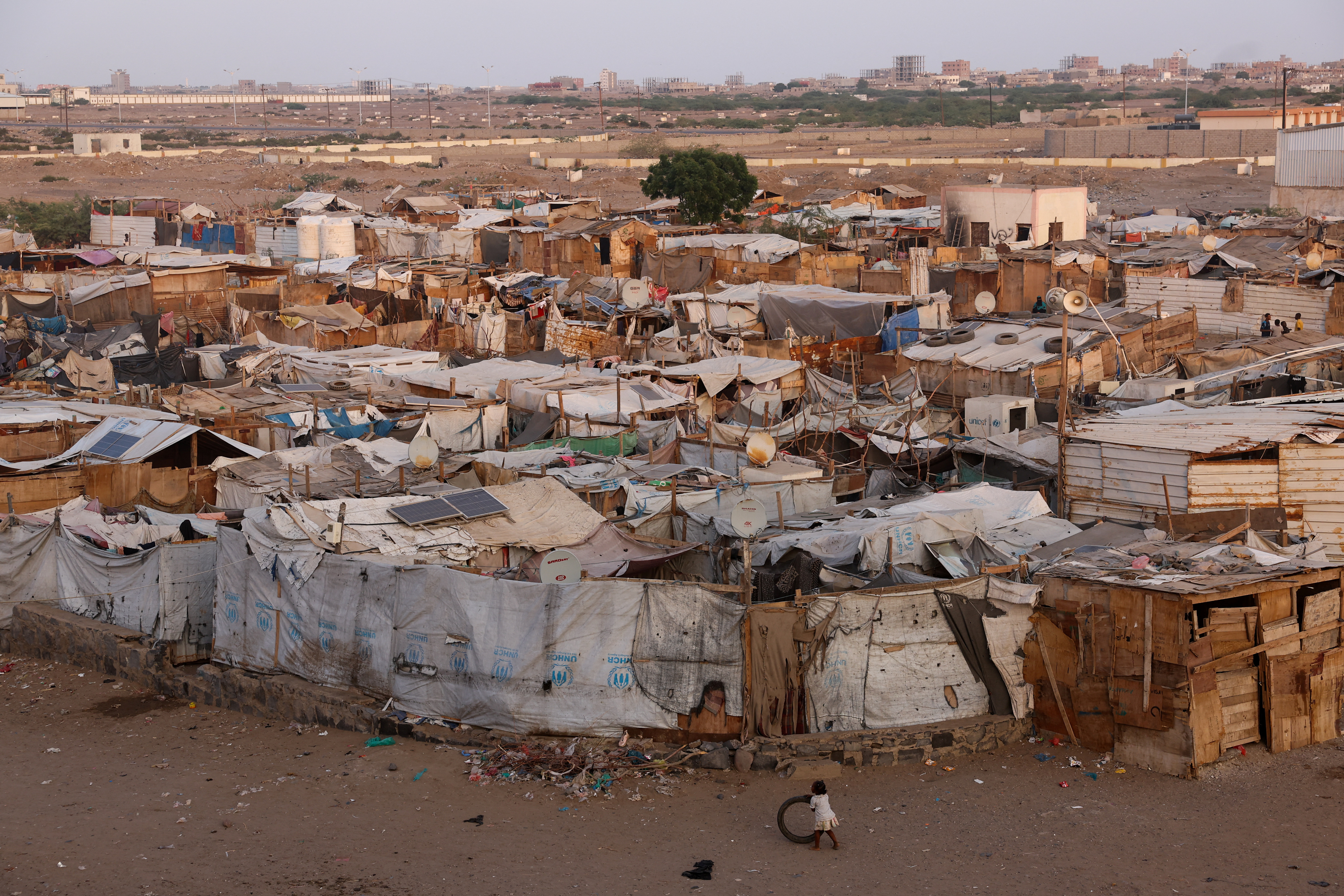 A girl plays with a tire next to a displaced persons camp in Aden