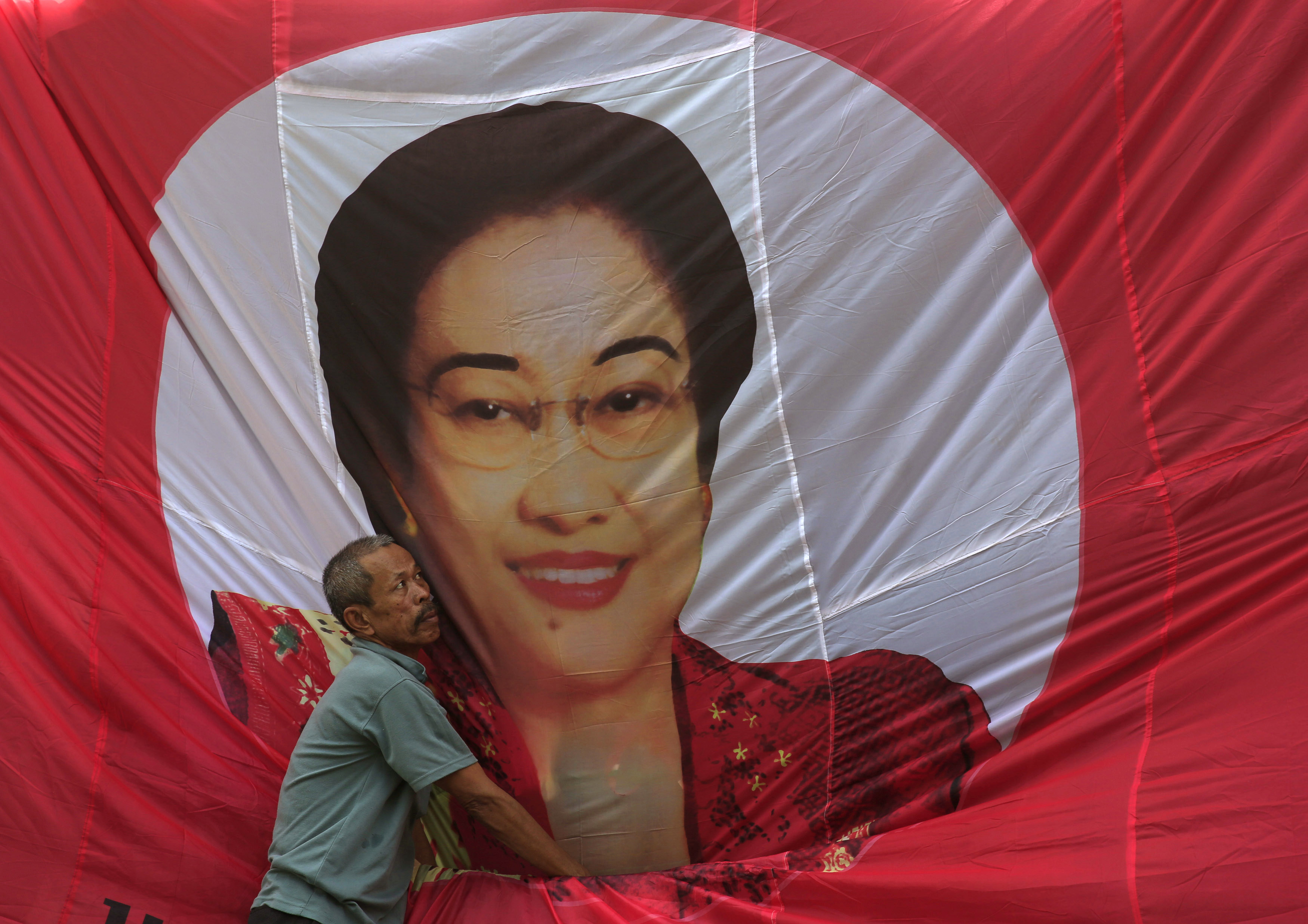 A man fixes a banner of Indonesia's former President Megawati Sukarnoputri in Jakarta