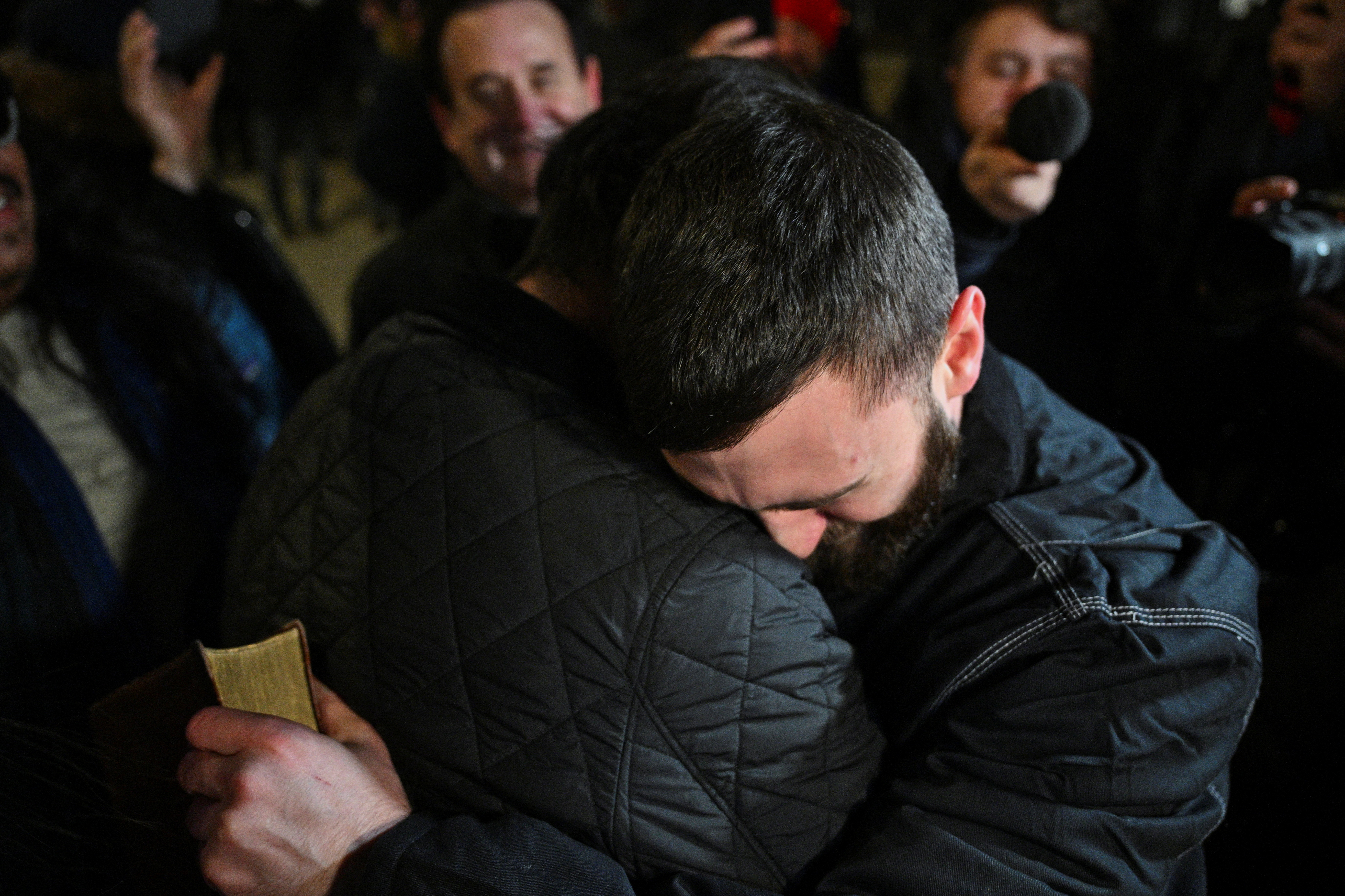 Edward "Jake" Lang, one of the defendants who was released after being pardoned, holds a bible while hugging a friend, in Washington