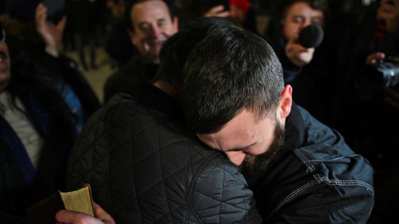 Edward "Jake" Lang, one of the defendants who was released after being pardoned, holds a bible while hugging a friend, in Washington