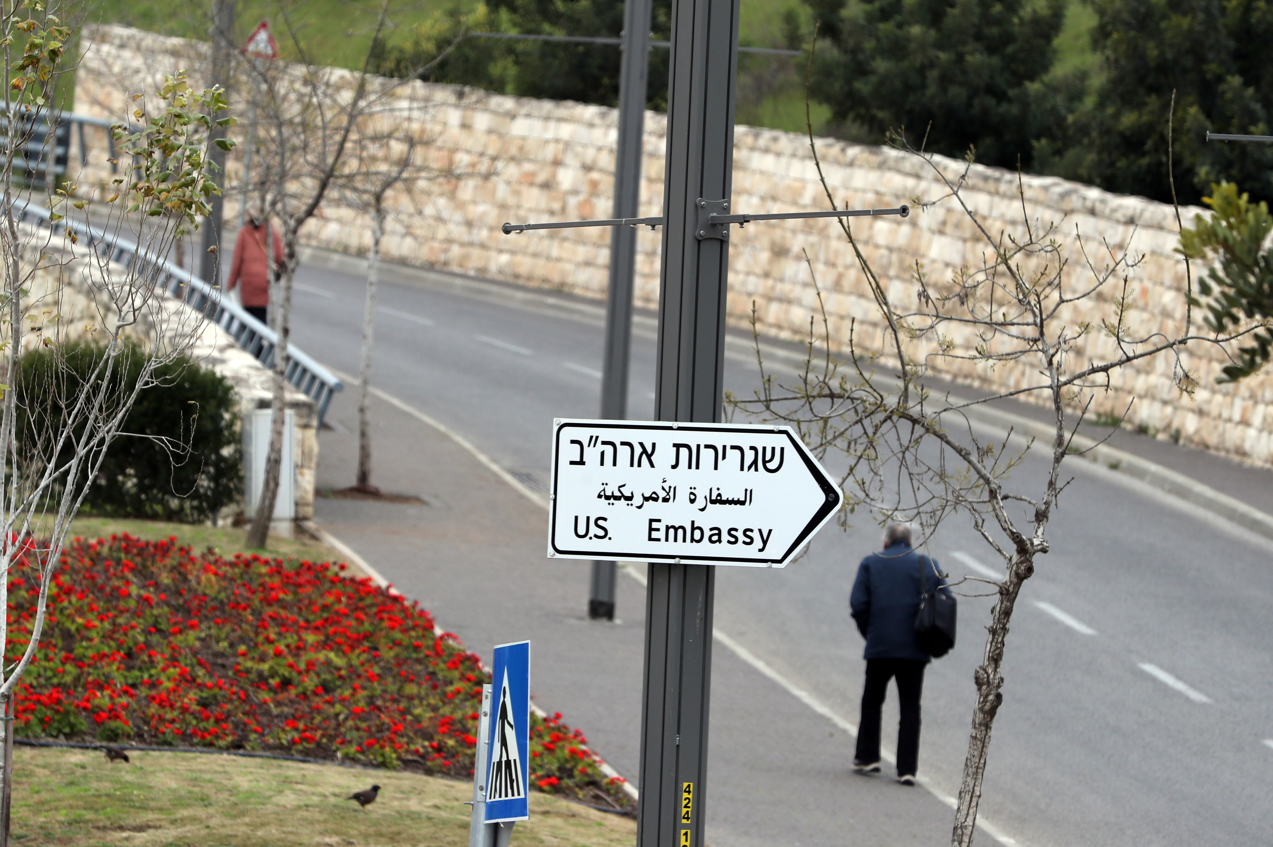 A man walks next to a road sign directing to the U.S. embassy in Jerusalem