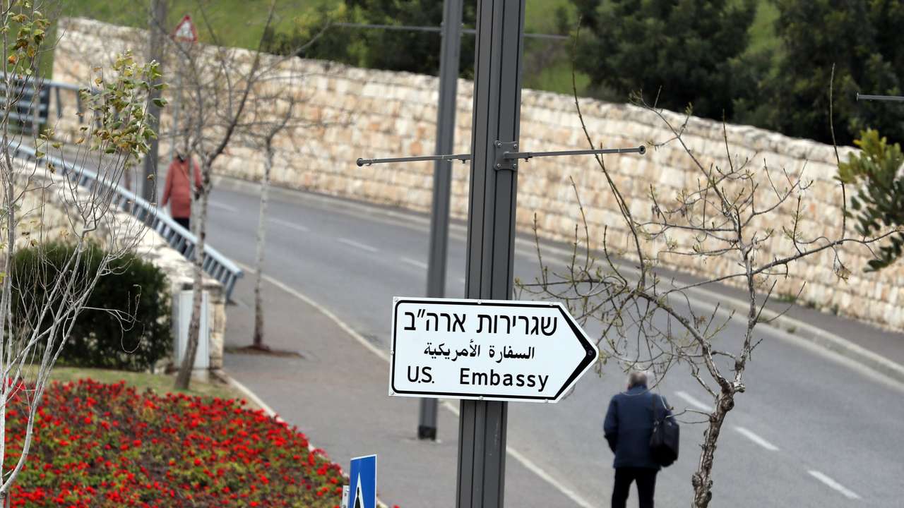A man walks next to a road sign directing to the U.S. embassy in Jerusalem