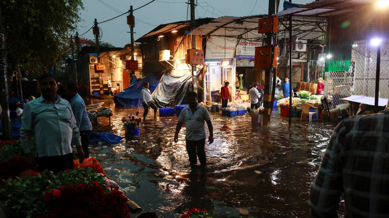 A man wades through a waterlogged street in a wholesale market after rain, in New Delhi