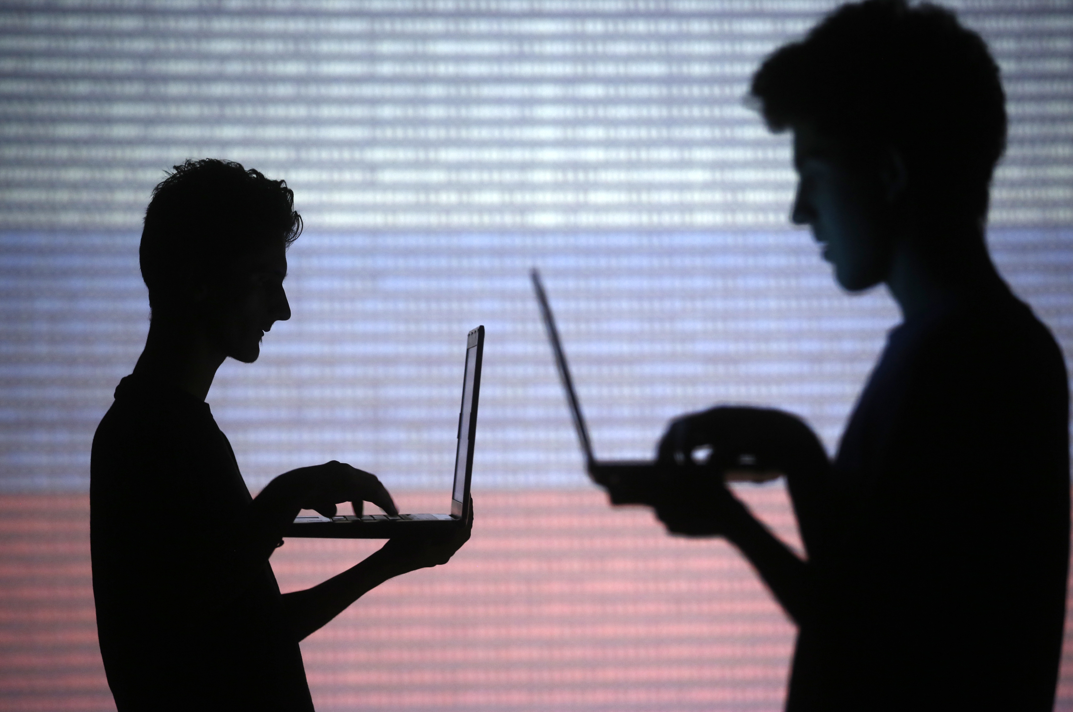 People pose with laptops in front of projection of binary code and a Russian national flag in this picture illustration taken in Zenica