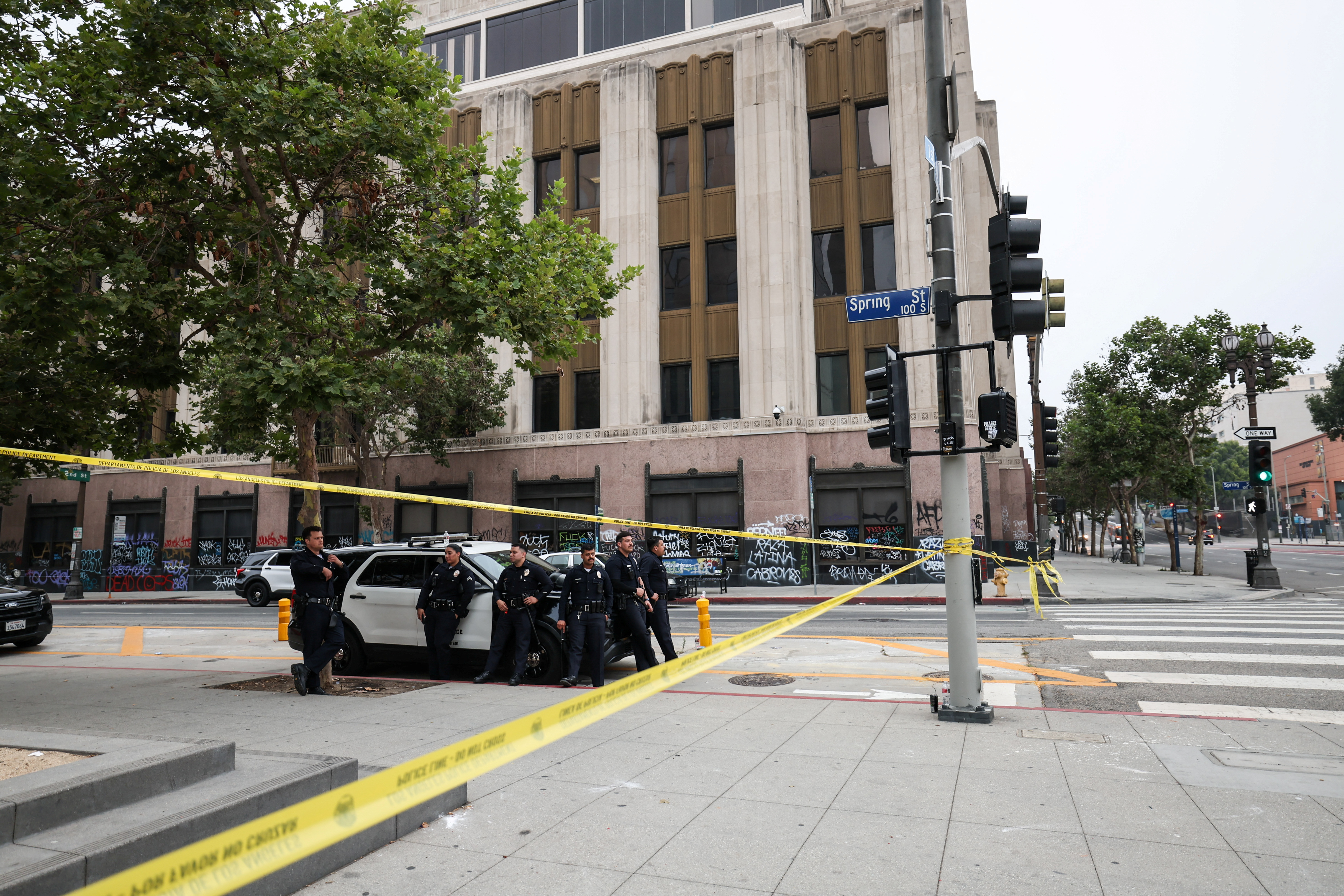 Members of law enforcement stand next to a police car, in Los Angeles
