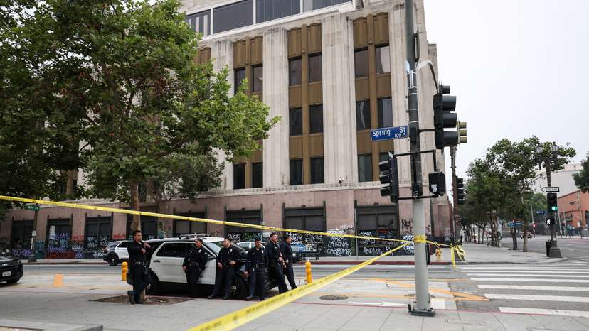 Members of law enforcement stand next to a police car, in Los Angeles