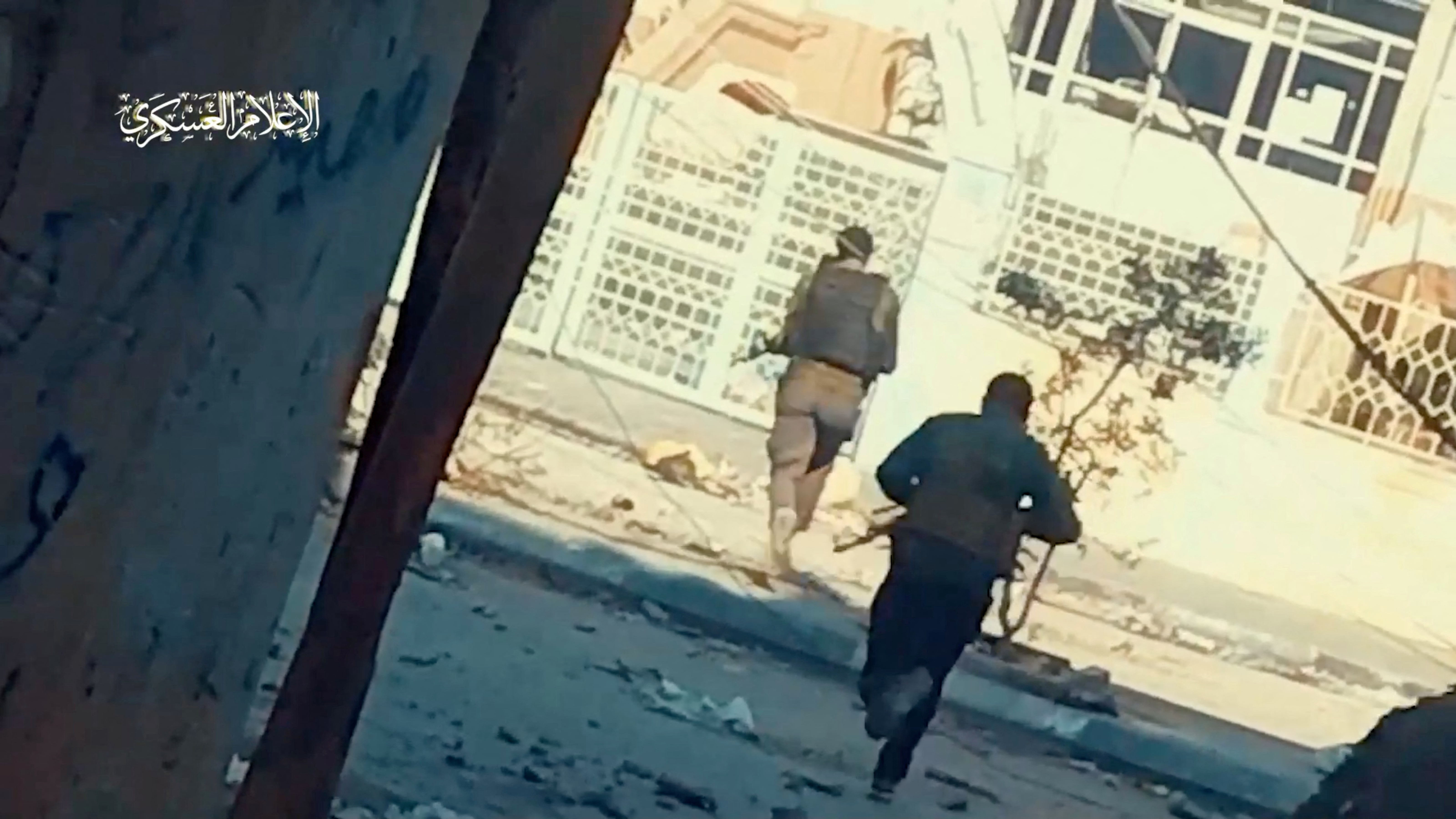 Hamas fighters run across the street at Rantissi hospital, in Gaza City
