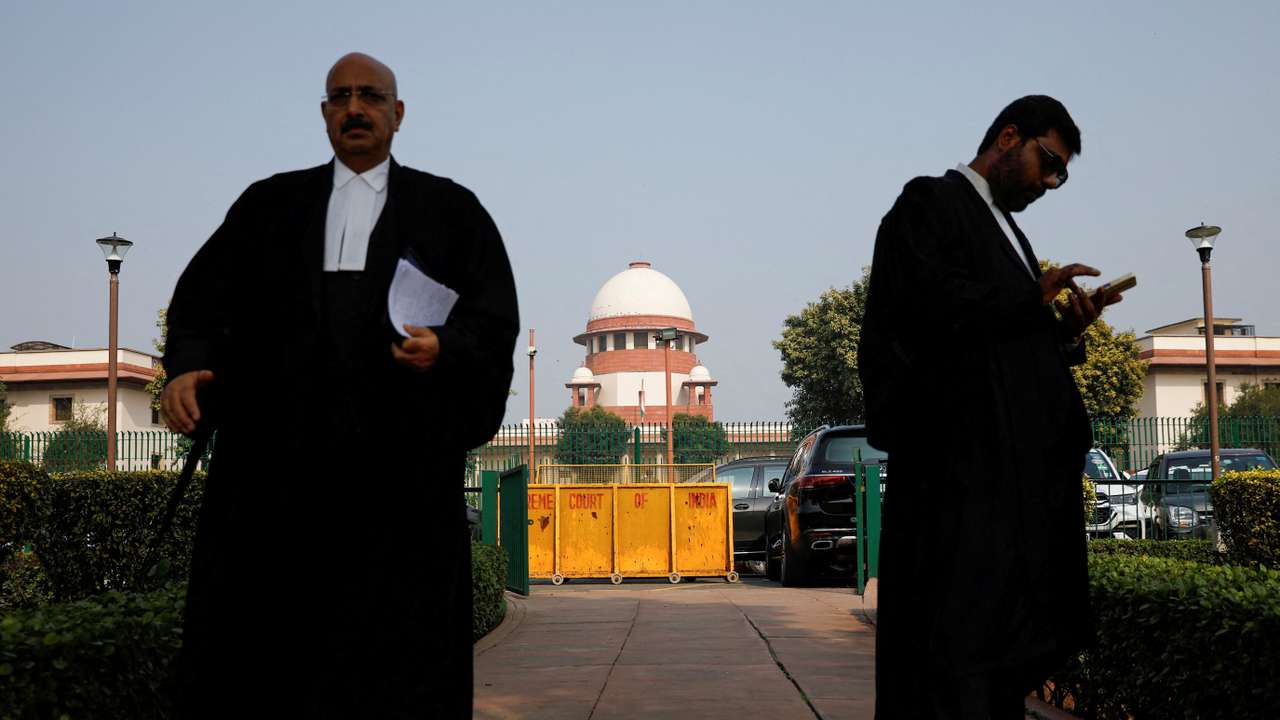 FILE PHOTO: A lawyer looks into his mobile phone as another walks past, in front of India's Supreme Court in New Delhi