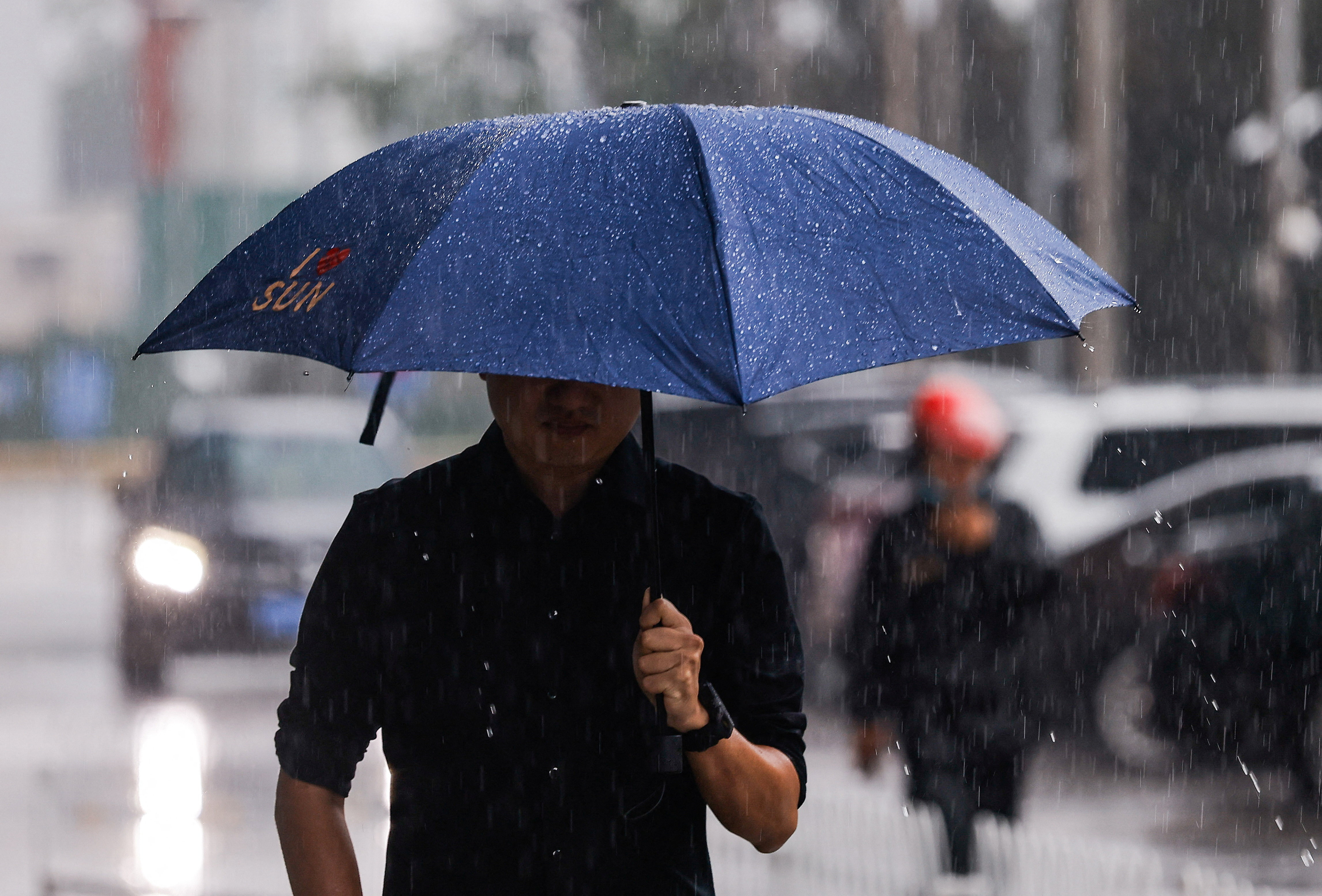 A man with an umbrella walks in the street during heavy rain in Beijing
