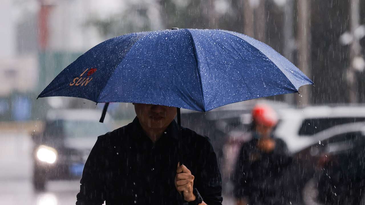 A man with an umbrella walks in the street during heavy rain in Beijing