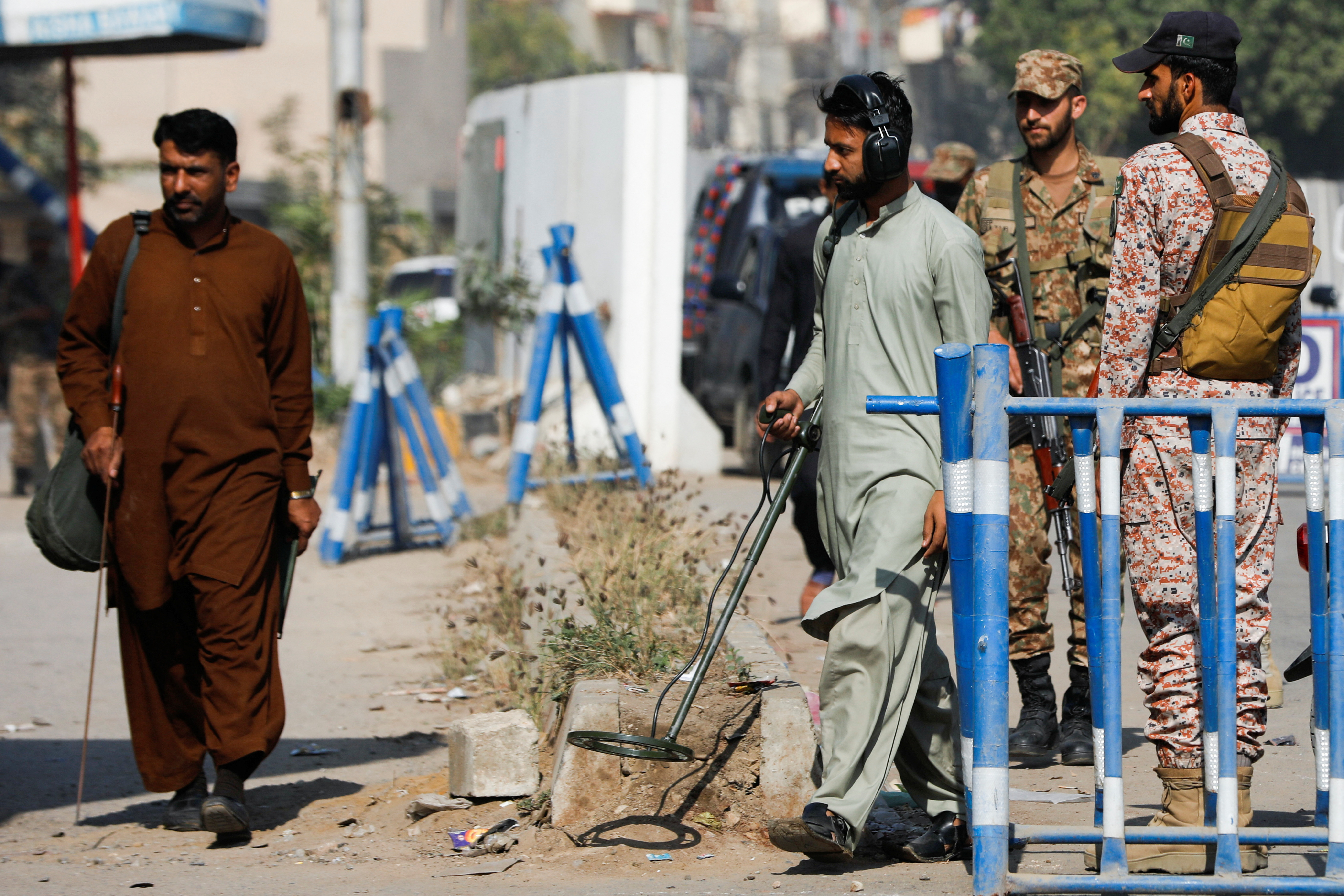 Members of the bomb disposal squad in plain clothes, survey the area after yesterday's attack on a police station, in Karachi