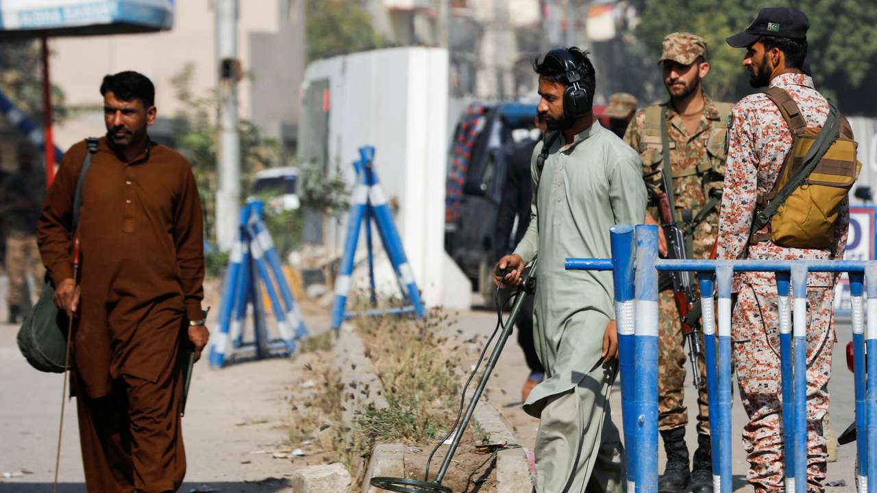 Members of the bomb disposal squad in plain clothes, survey the area after yesterday's attack on a police station, in Karachi