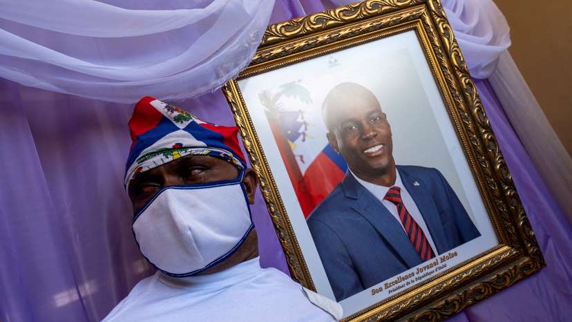 FILE PHOTO: A man stands next to a portrait of slain Haitian President Jovenel Moise placed on a memorial at the city hall in Cap-Haitien
