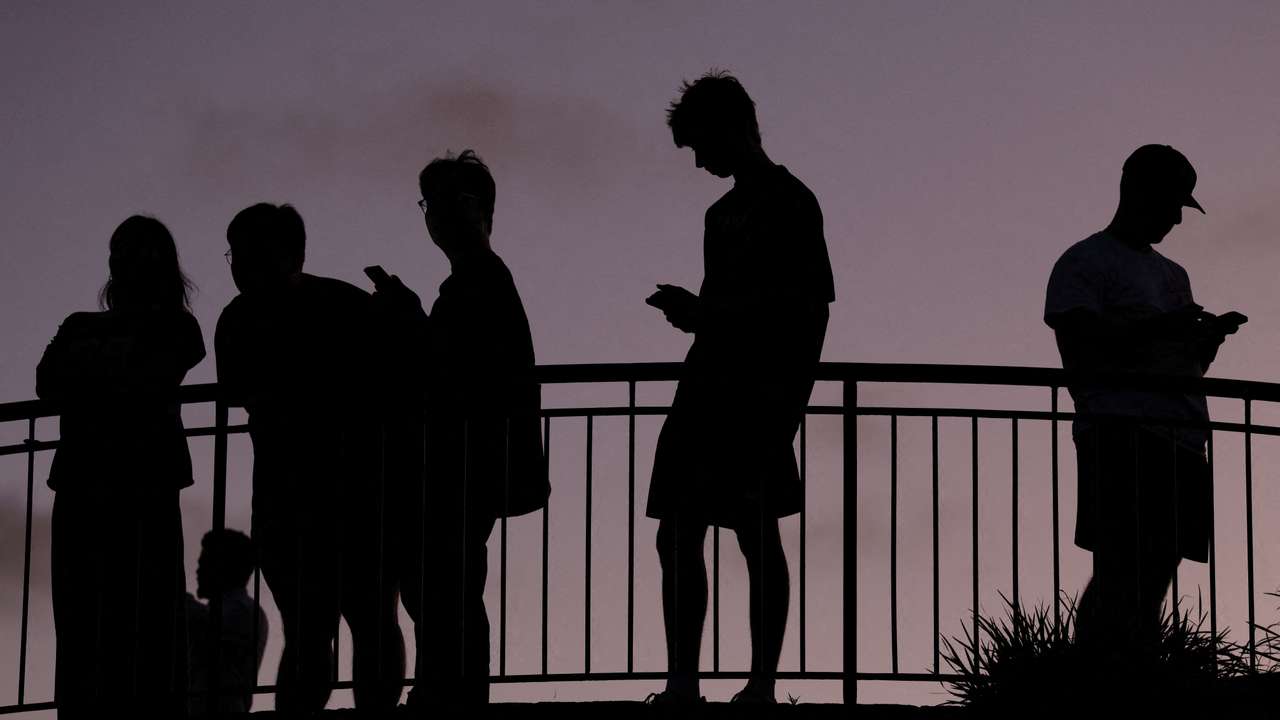 People use their mobile phones at dusk in Brisbane
