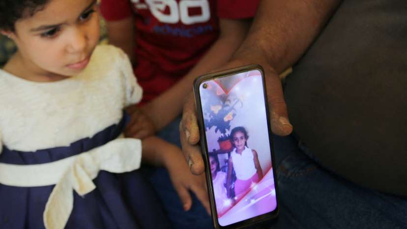Amar, father of Algerian boxer Imane Khelif, sits with his children as he shows a picture of Imane when she was young, inside his house