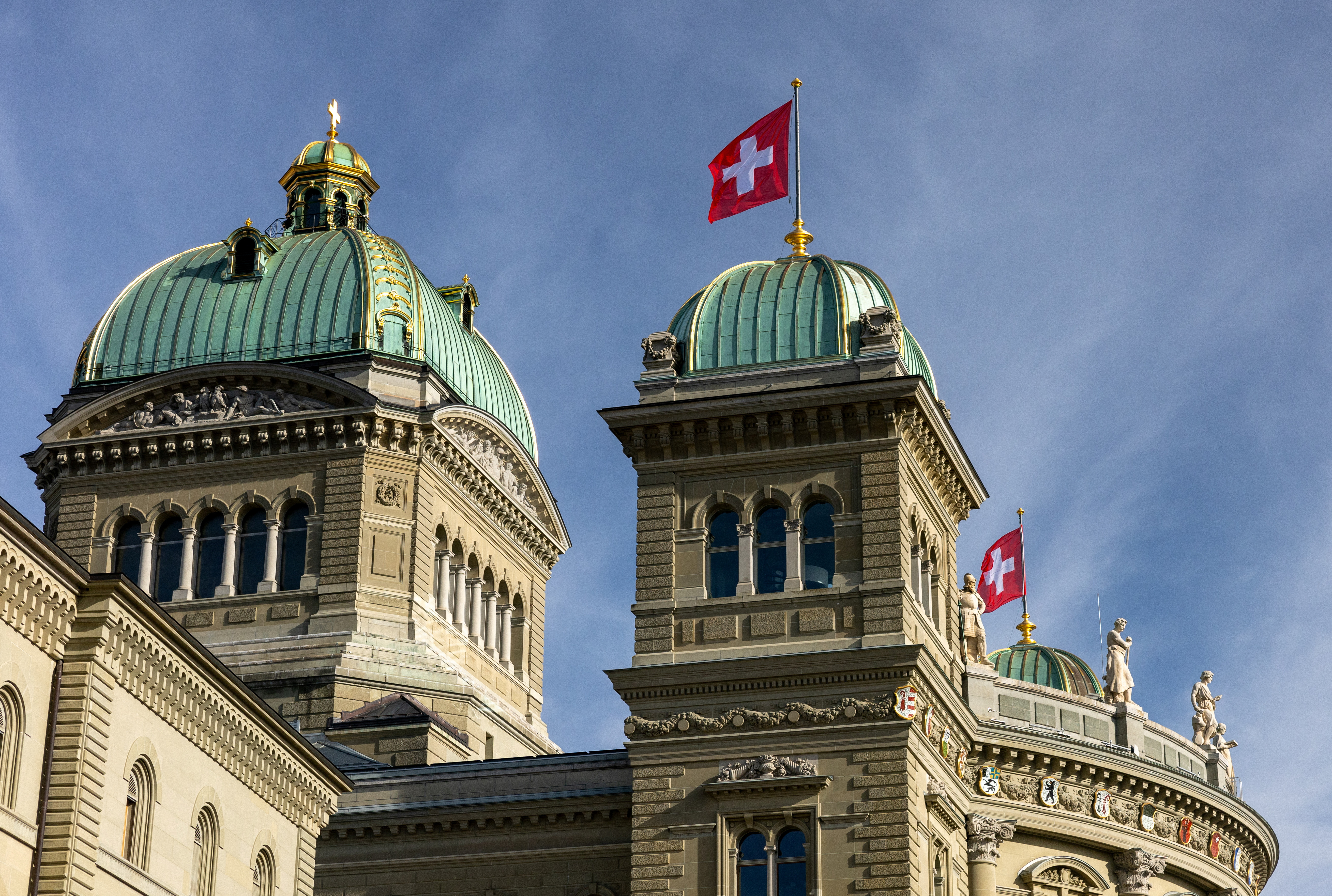 Swiss flags flutter on the Swiss Parliament Building (Bundeshaus) in Bern